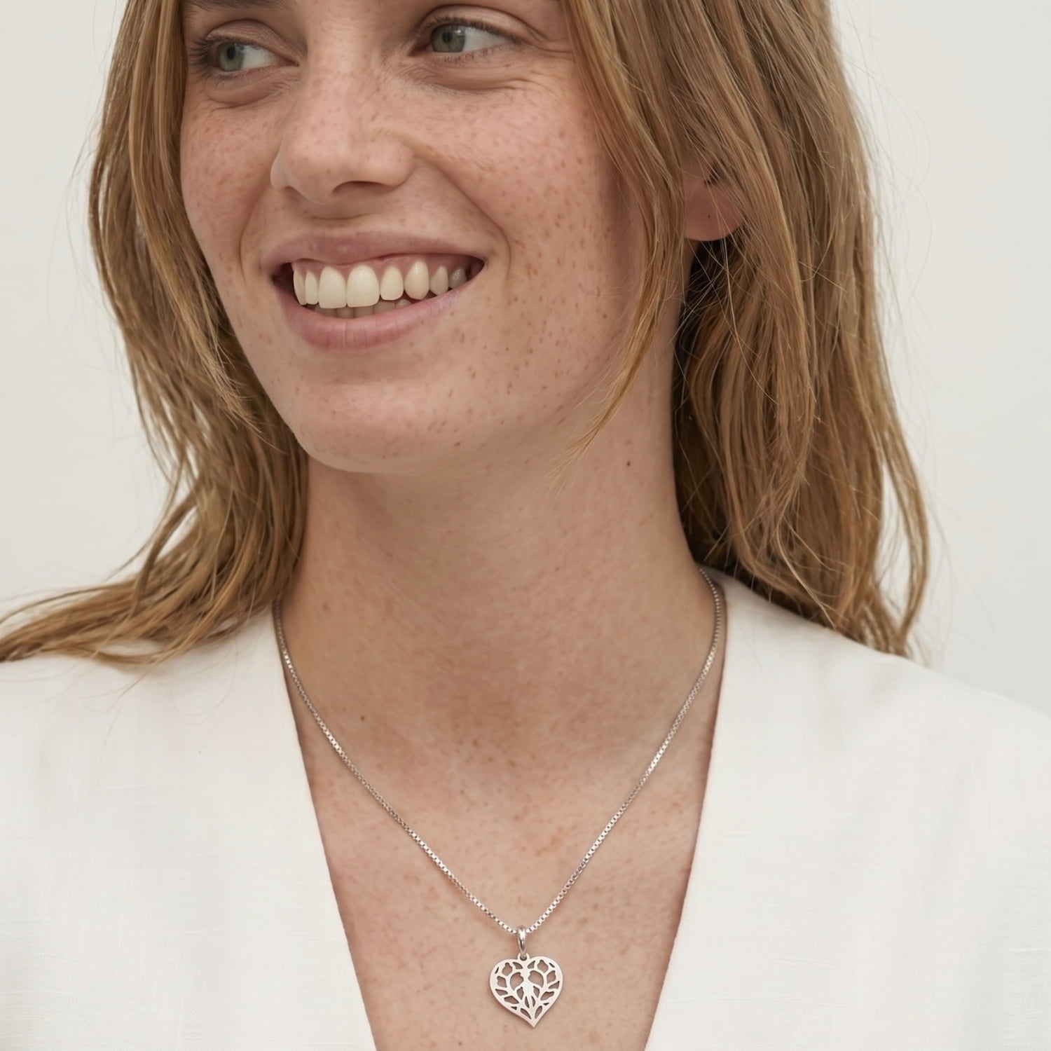Woman wears a sterling silver pendant featuring an openwork heart design inspired by Yorkshire, suspended from a fine box chain, showcasing delicate sculptural craftsmanship.