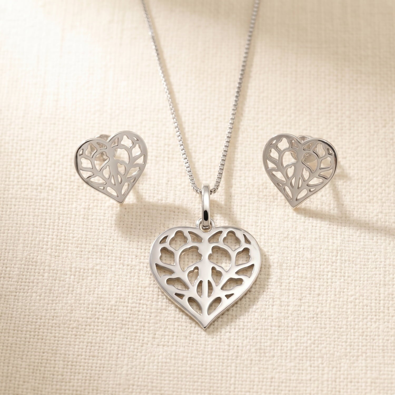 Pair of sterling silver stud earrings with detailed openwork heart design inspired by Yorkshire, accompanied by a matching pendant on a fine silver chain, showcasing expert craftsmanship.