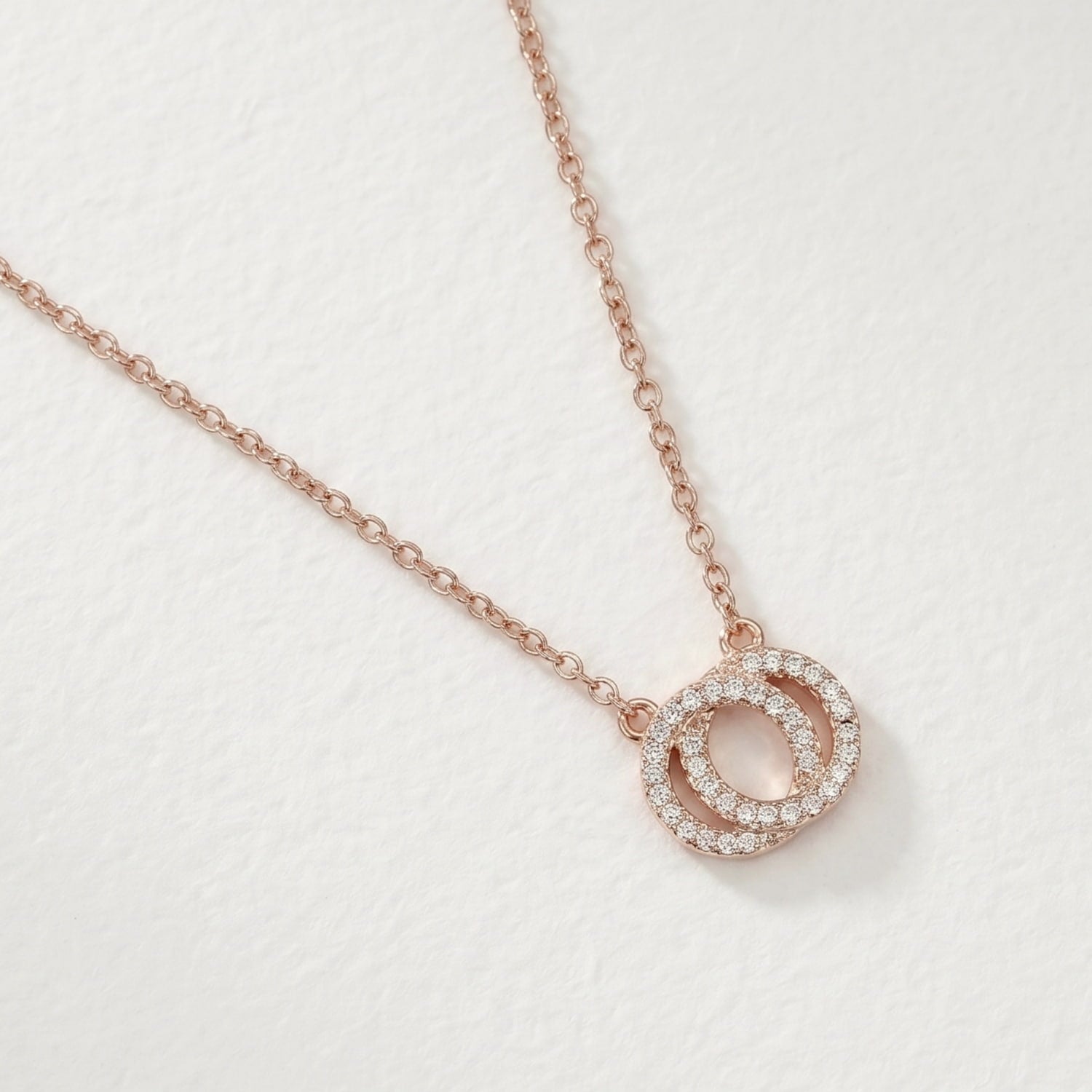 Rose gold necklace with an interlocking circular pendant.
