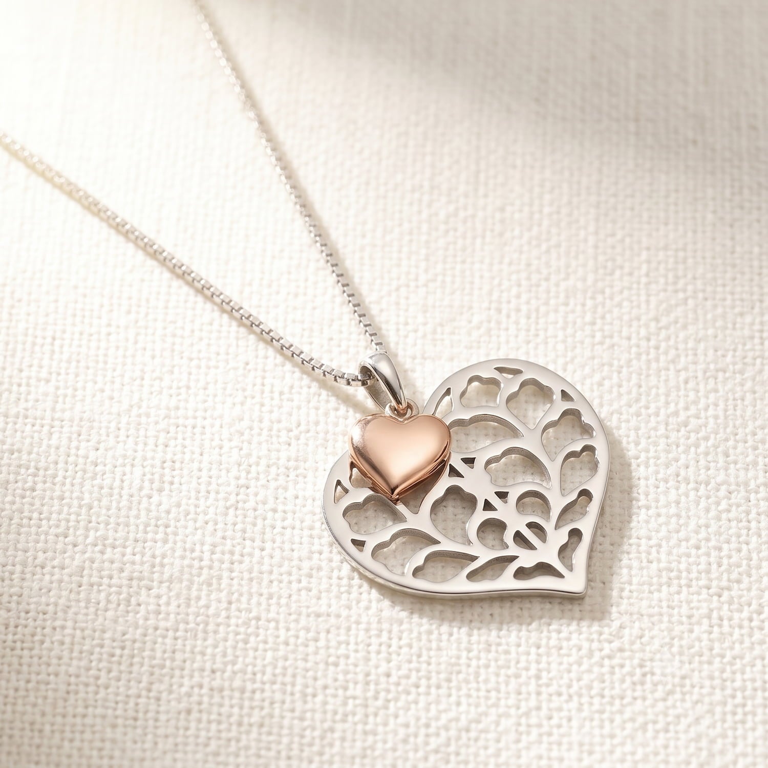 Sterling silver necklace featuring a sculptural openwork heart pendant accented with a small rose gold vermeil heart, suspended on a fine chain for elegant wear.