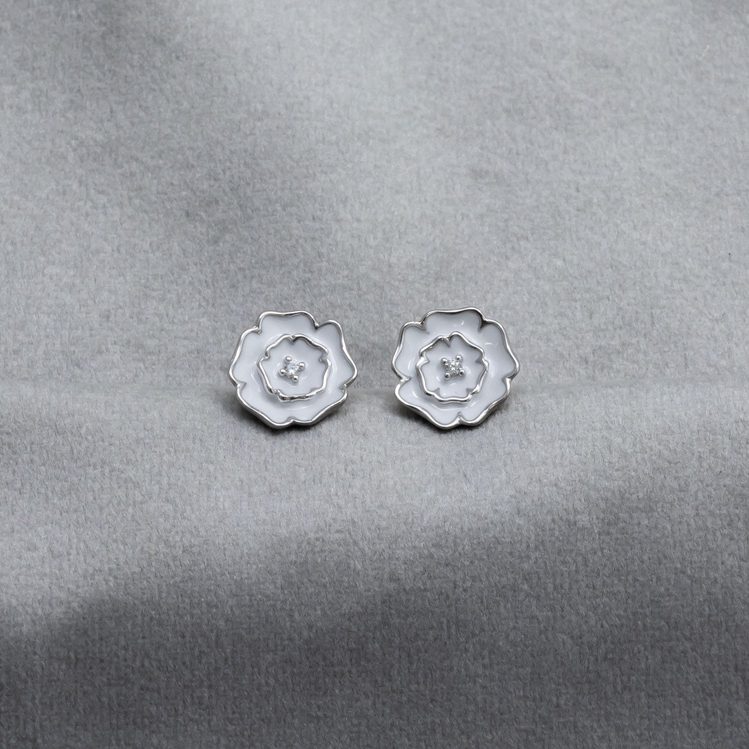Pair of sterling silver stud earrings designed as Yorkshire roses with white enamel detailing, showcasing a delicate and sculptural floral motif.