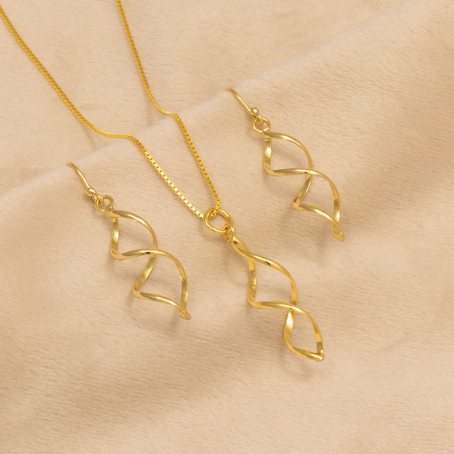 Set of yellow gold vermeil jewellery featuring a longer open twist pendant necklace paired with matching twisted drop earrings, showcasing elegant sculptural design.