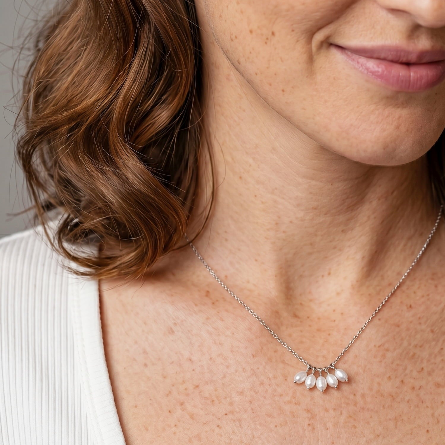 A silver necklace with a cluster of baroque freshwater pearls at the bottom.