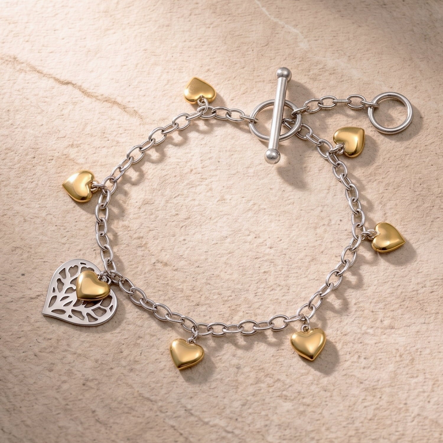 Sterling silver chain bracelet featuring a T-bar fastening, adorned with polished yellow gold vermeil heart charms and an openwork silver heart detail.