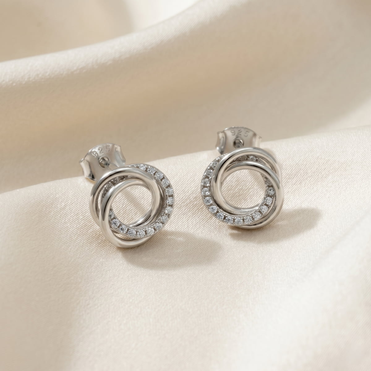 Sterling silver stud earrings featuring an elegant intertwined knot design accented with pavé-set stones, showcasing a refined and sculptural aesthetic in silver jewellery.