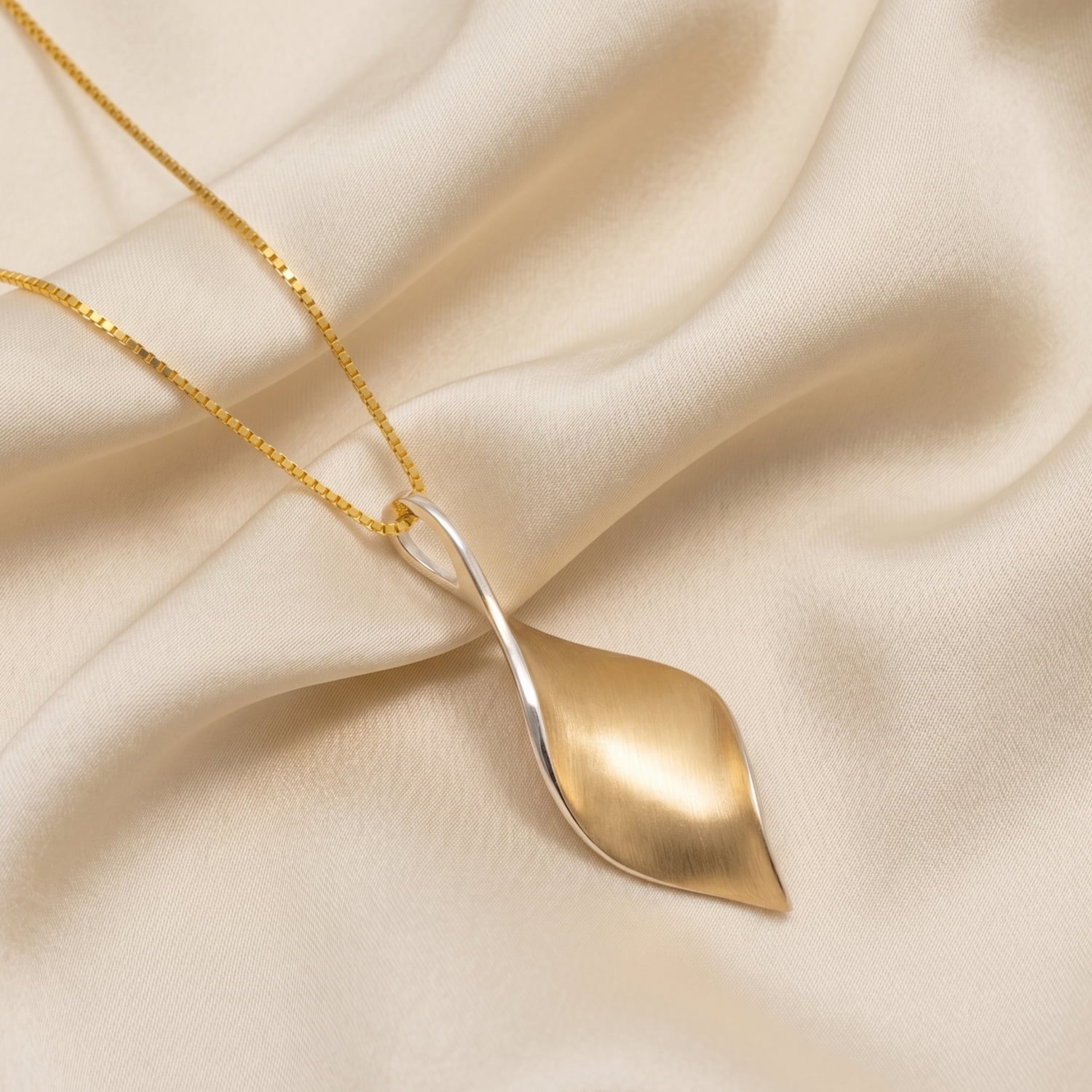 Yellow gold vermeil twist pendant on cream silk background