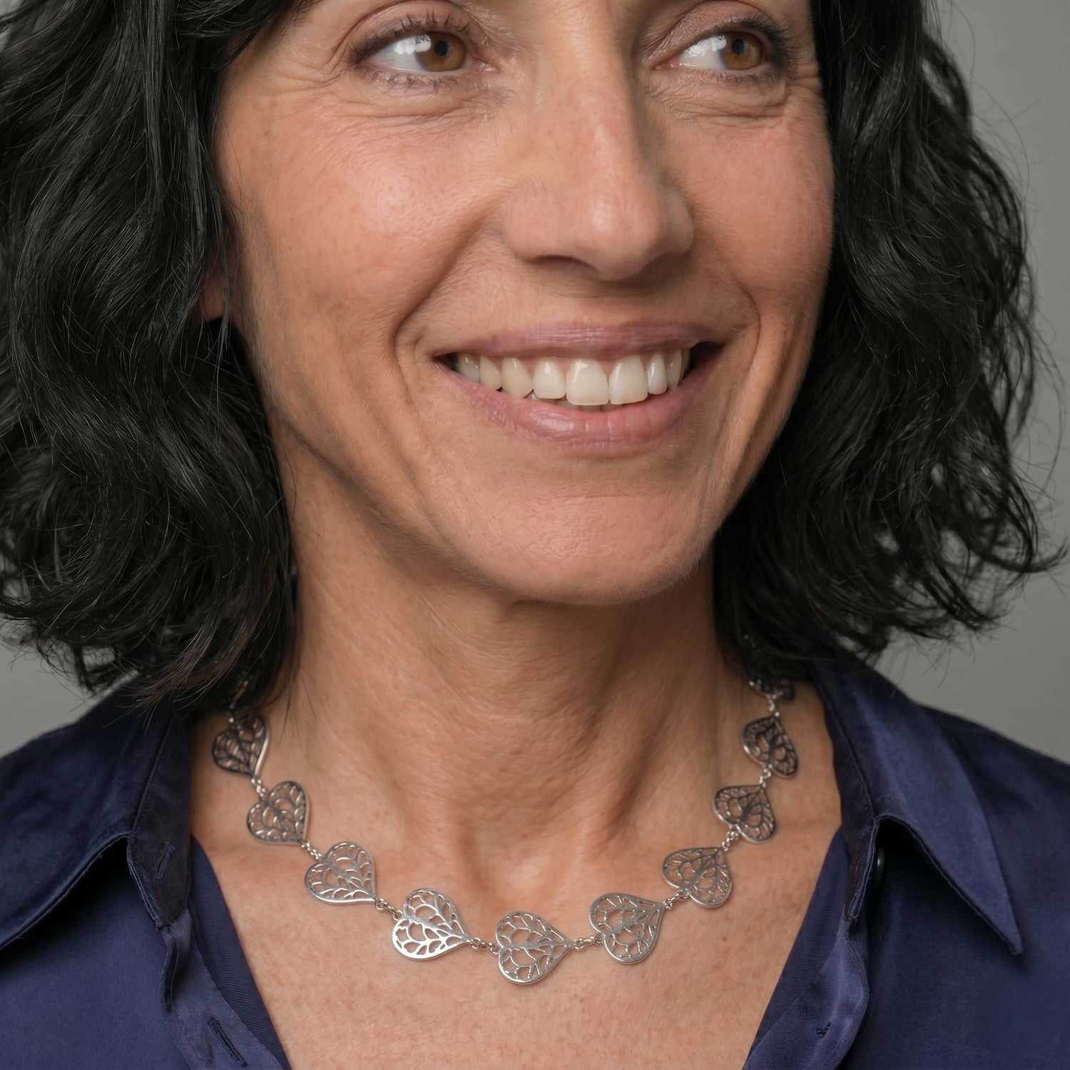 Necklace featuring linked sterling silver openwork hearts with delicate filigree detailing, styled to sit gracefully along the neckline for an elegant, contemporary look.