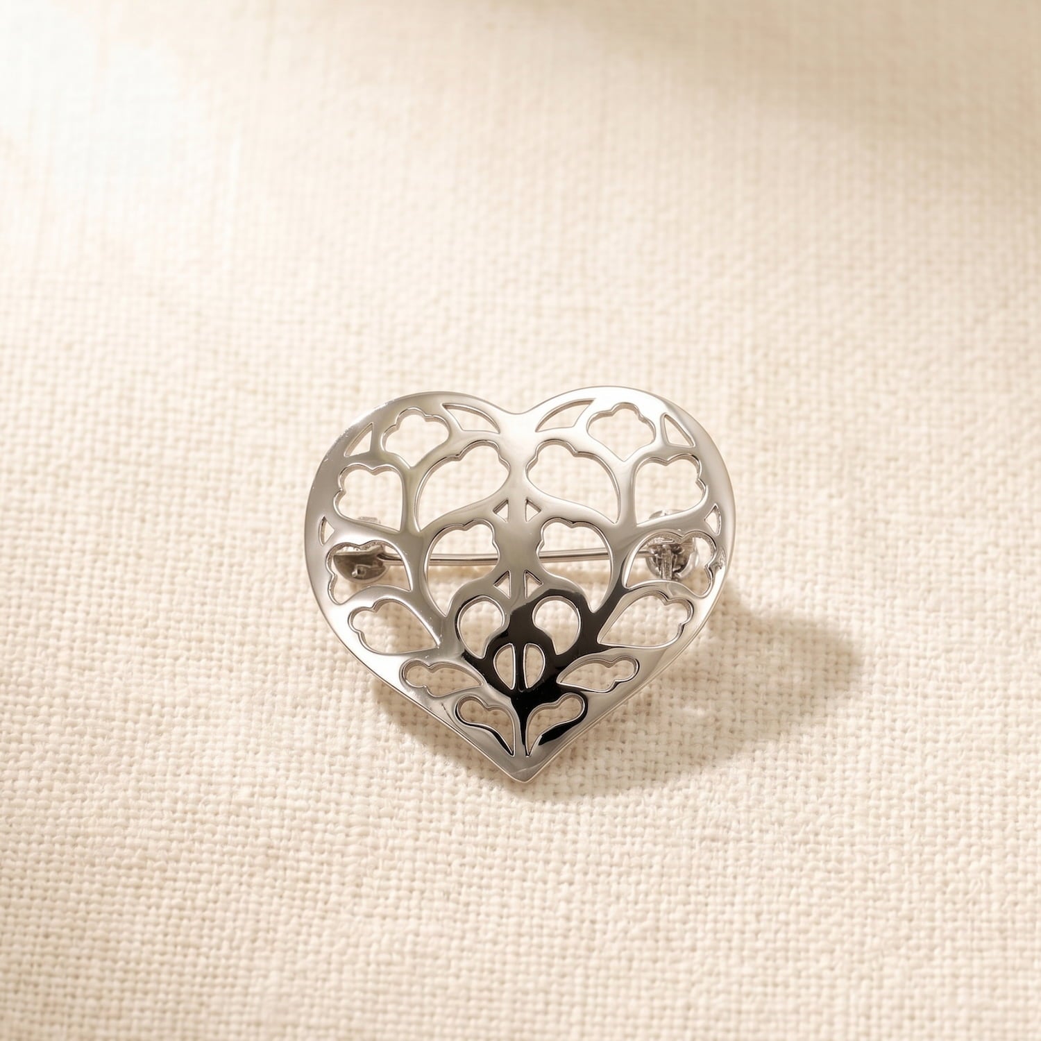 Sterling silver brooch featuring an openwork heart design inspired by Yorkshire, with a sculptural and elegant silhouette, resting on soft white fabric.
