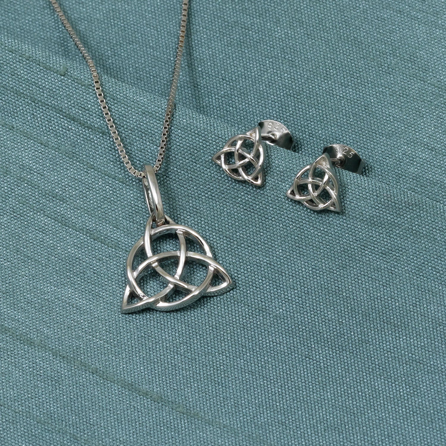 Sterling silver stud earrings and matching pendant featuring an openwork Celtic trinity knot design, showcasing refined sculptural details in contemporary silver jewellery.