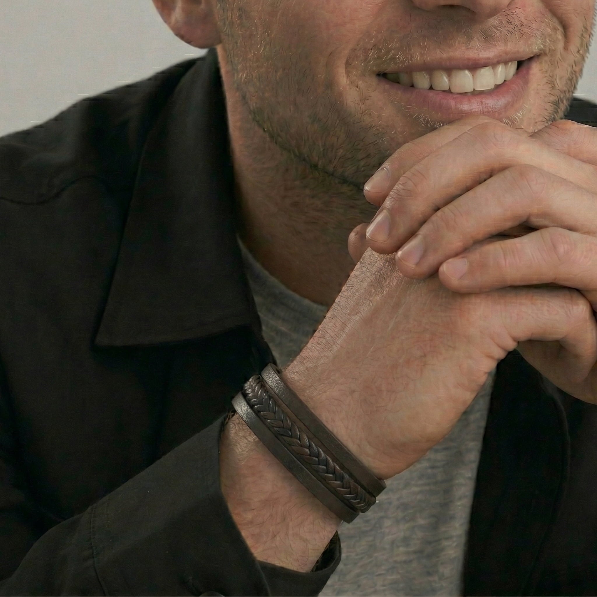 Man wearing a triple strand leather bracelet with a neutral background
