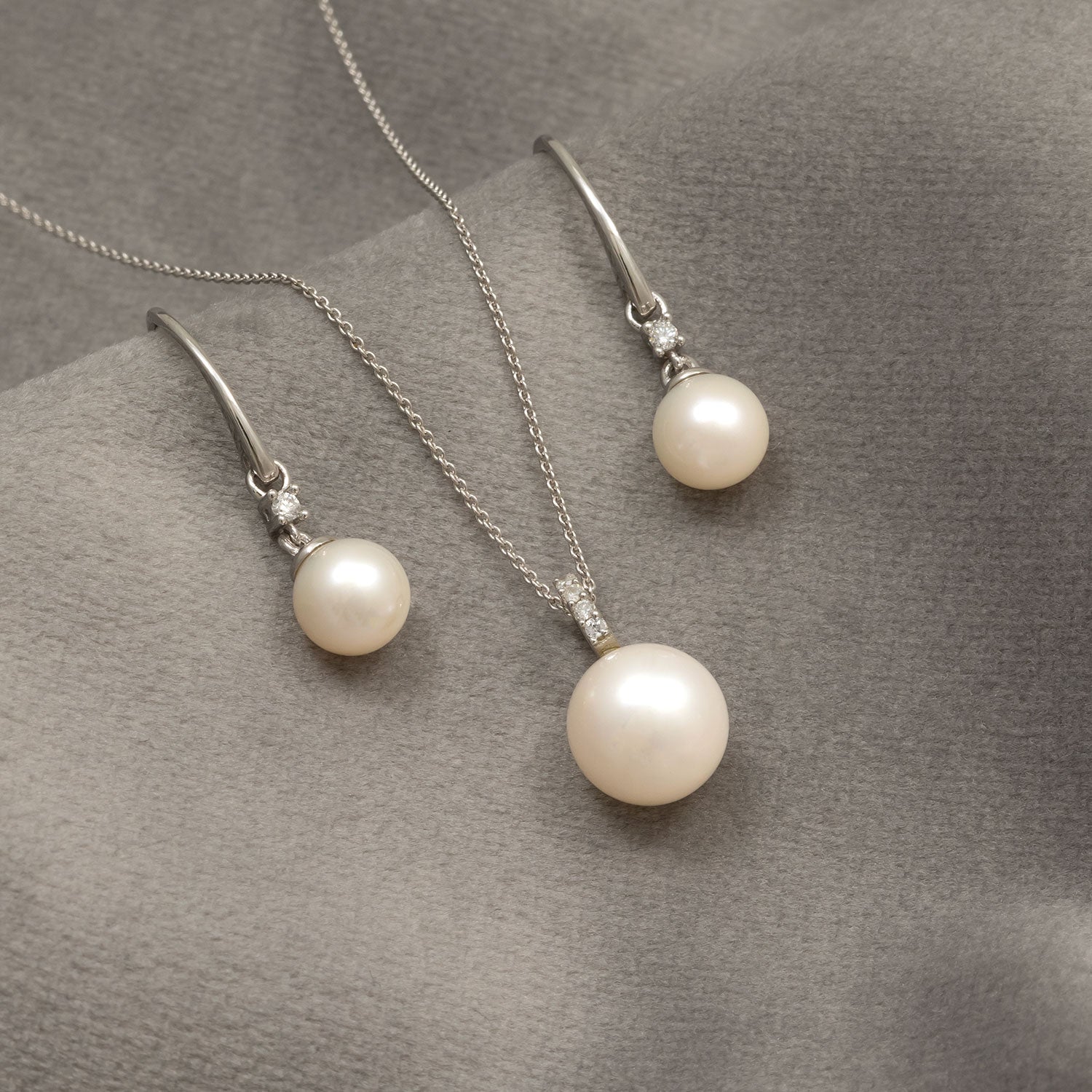 Set of 9ct white gold drop earrings and matching pendant necklace showcasing lustrous pearls accented with delicate diamonds, highlighting refined elegance in fine jewellery design.