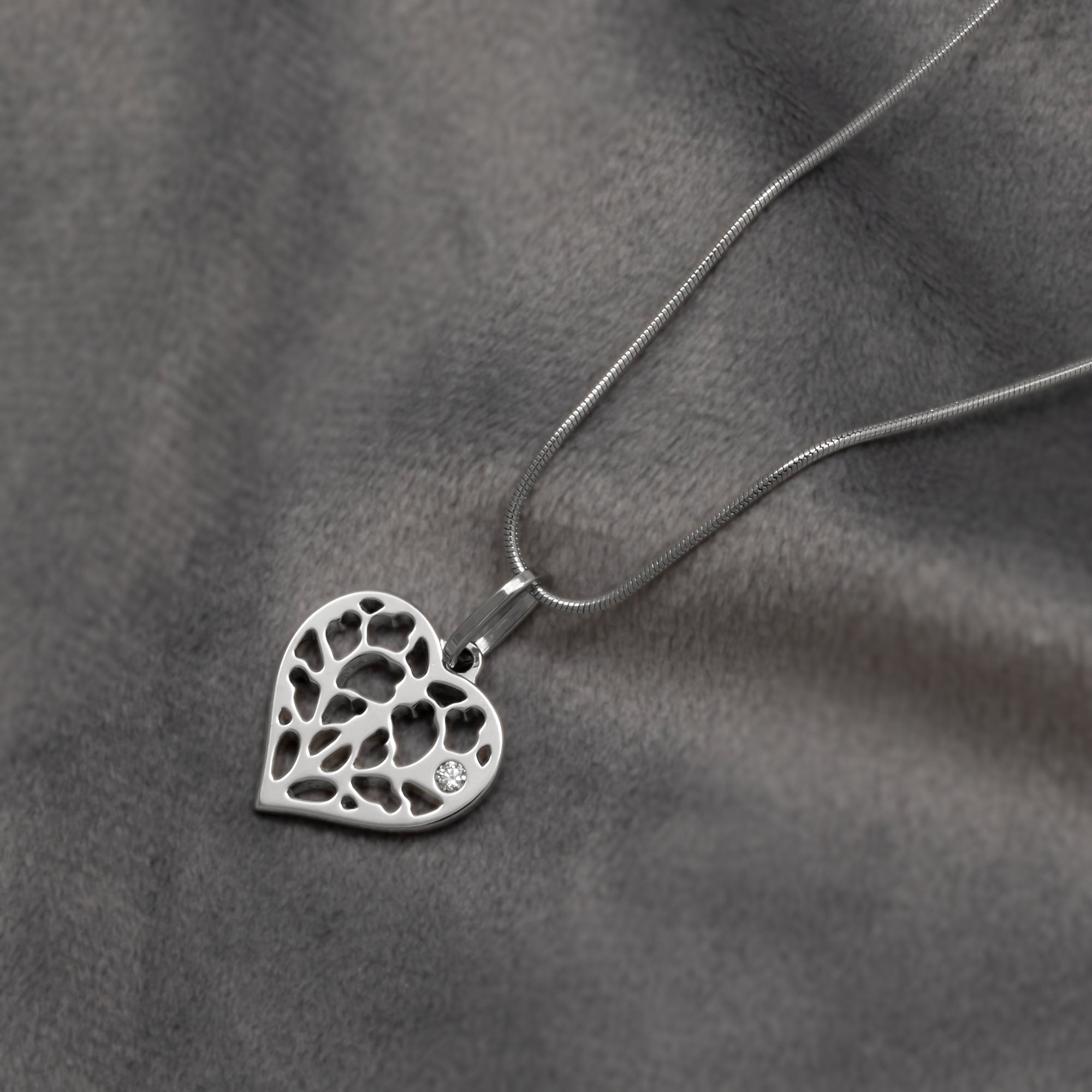 9 carat white gold heart-shaped pendant featuring delicate openwork design based on York Minster with diamond accents on a snake chain, showcasing refined contemporary craftsmanship. Place on a grey velvet cloth.
