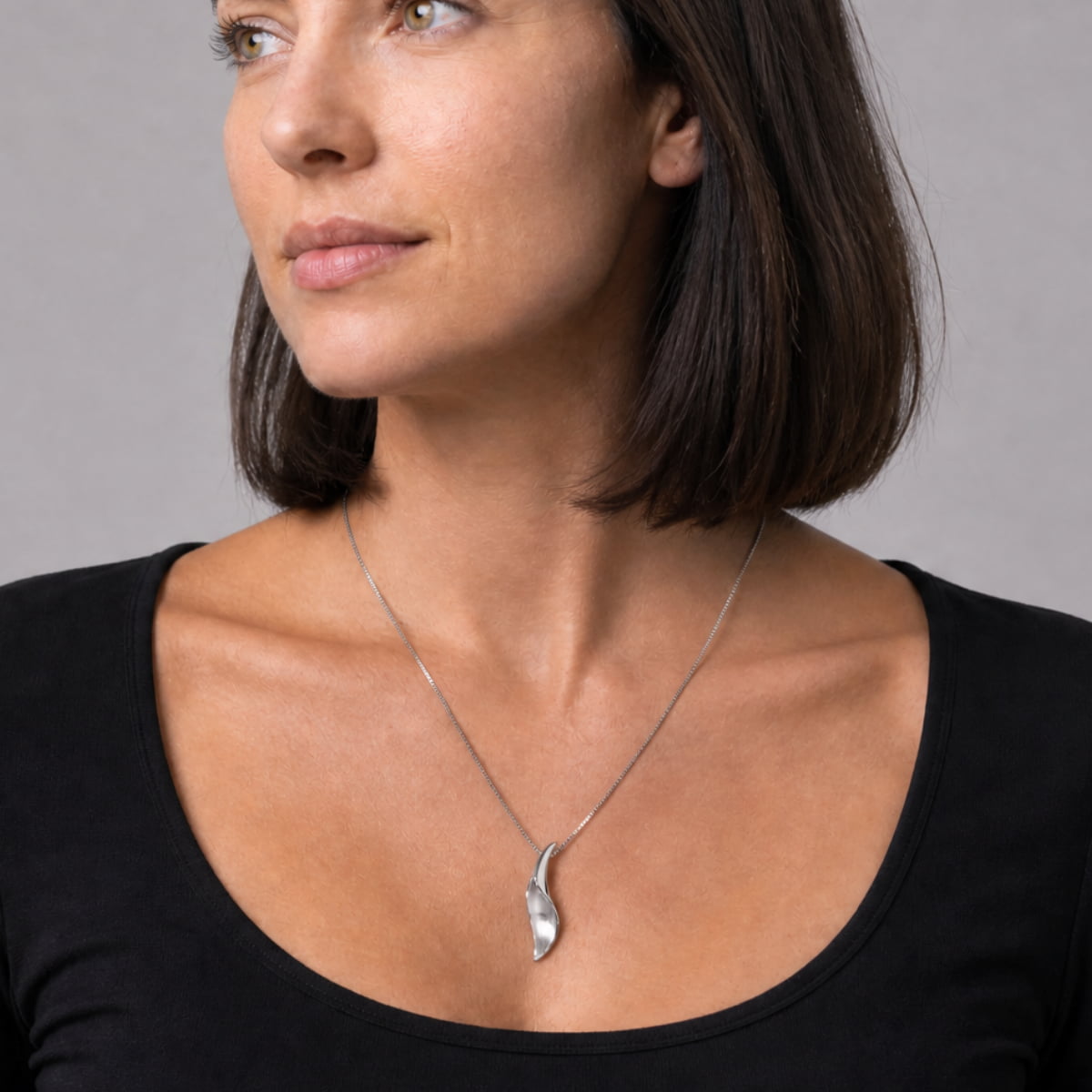 Sterling silver pendant featuring a folded, curved design with contrasting satin and polished finishes, suspended from a delicate chain for refined contemporary elegance.