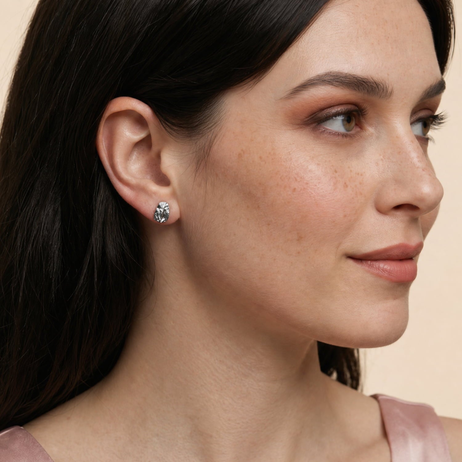Model wears a pair of sterling silver stud earrings inspired by natural pebble shapes, featuring subtle textured surfaces for a modern and sculptural jewellery look.