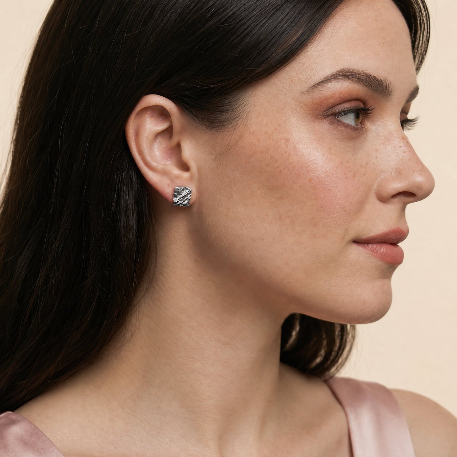 Model wears a pair of sterling silver rectangle stud earrings with a textured, hammered finish, showcasing a contemporary and sculptural design in fine silver jewellery.