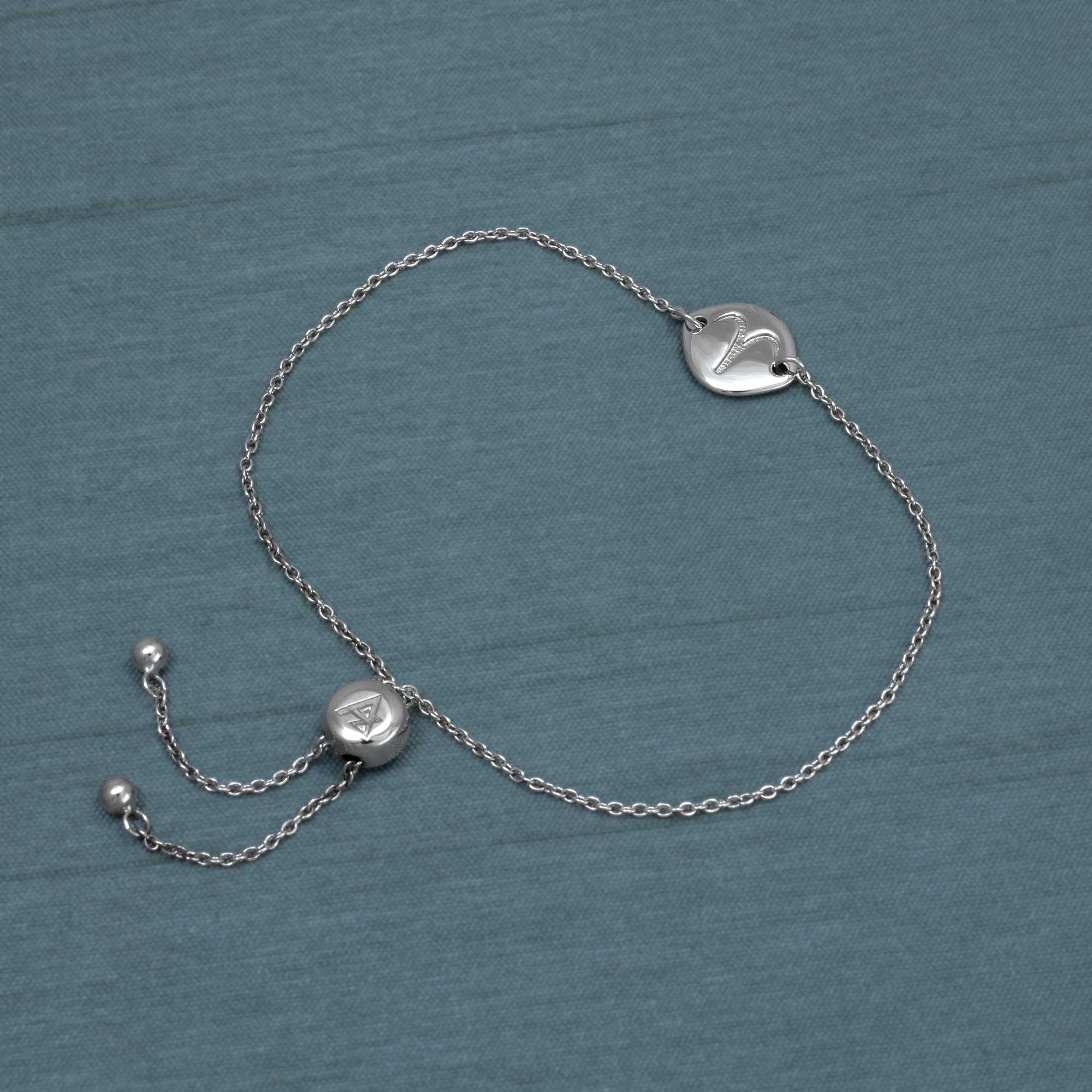Delicate sterling silver bracelet featuring an adjustable sliding bead and a sculptural Aries zodiac charm with a polished finish, laid flat on a soft grey surface.
