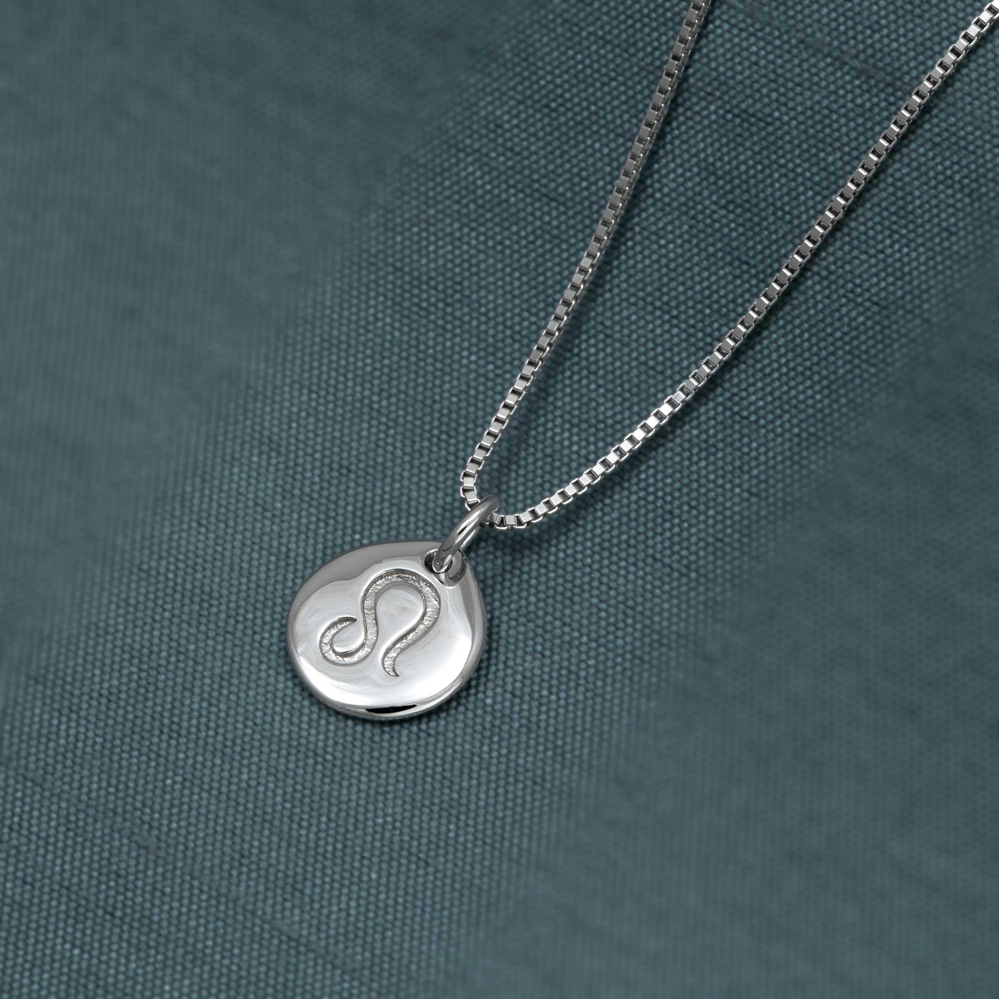 Sterling silver pendant featuring a sculptural Leo zodiac symbol with a polished finish, suspended from a delicate box chain on a textured dark background.
