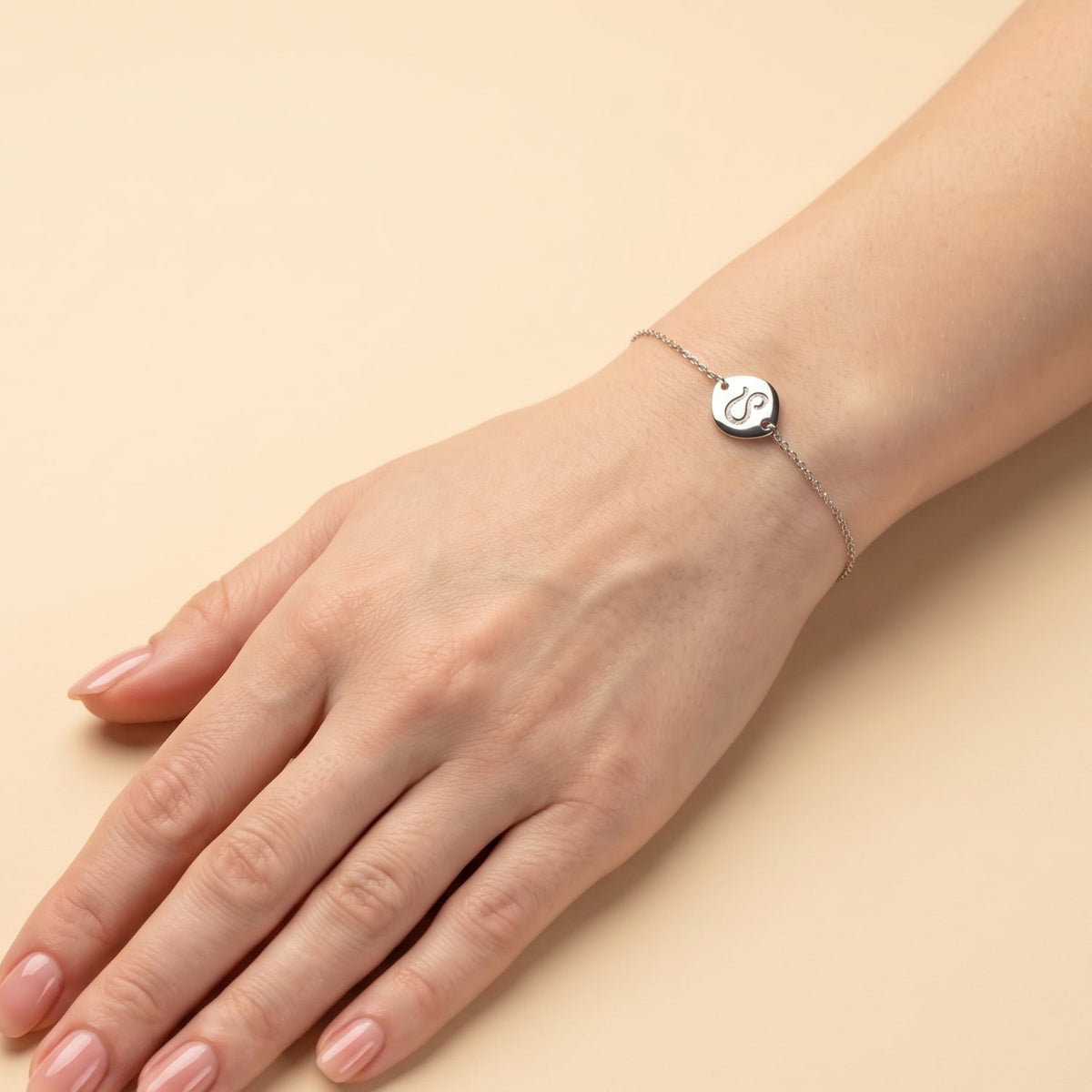 Delicate sterling silver bracelet featuring an adjustable chain with a polished Leo zodiac charm, worn on the wrist against a purple background.