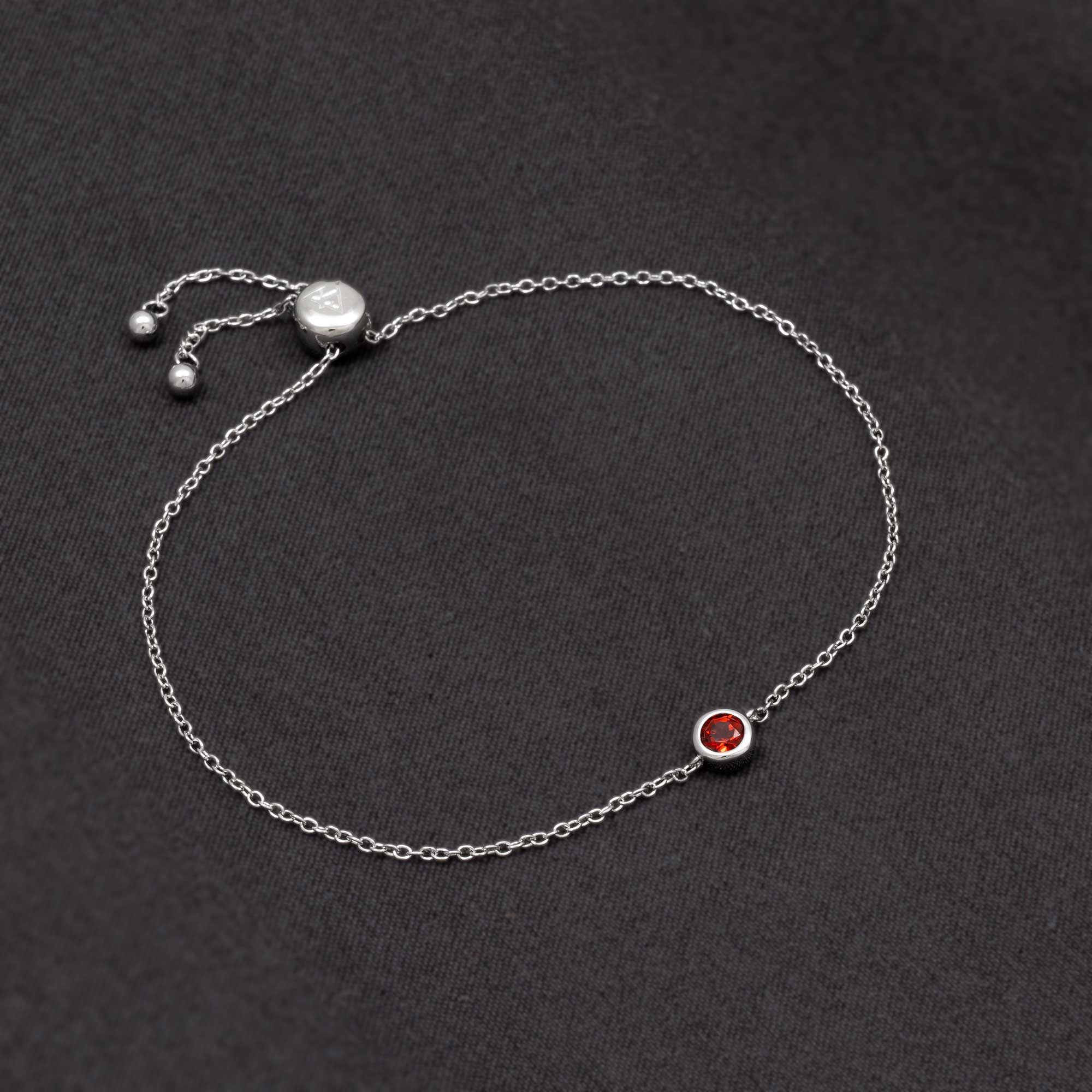 Delicate sterling silver bracelet featuring a deep red garnet birthstone set in a minimalist bezel on a fine adjustable chain, embodying elegant British craftsmanship.