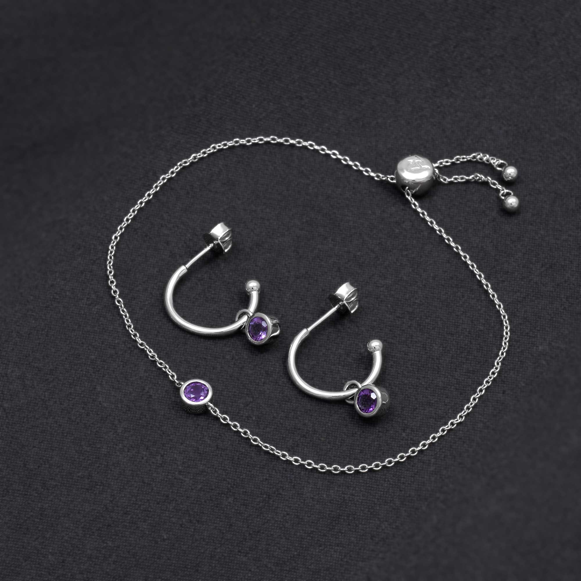 Pair of sterling silver hoop earrings featuring vibrant amethyst stones, complemented by a matching delicate chain bracelet for a coordinated, elegant look.