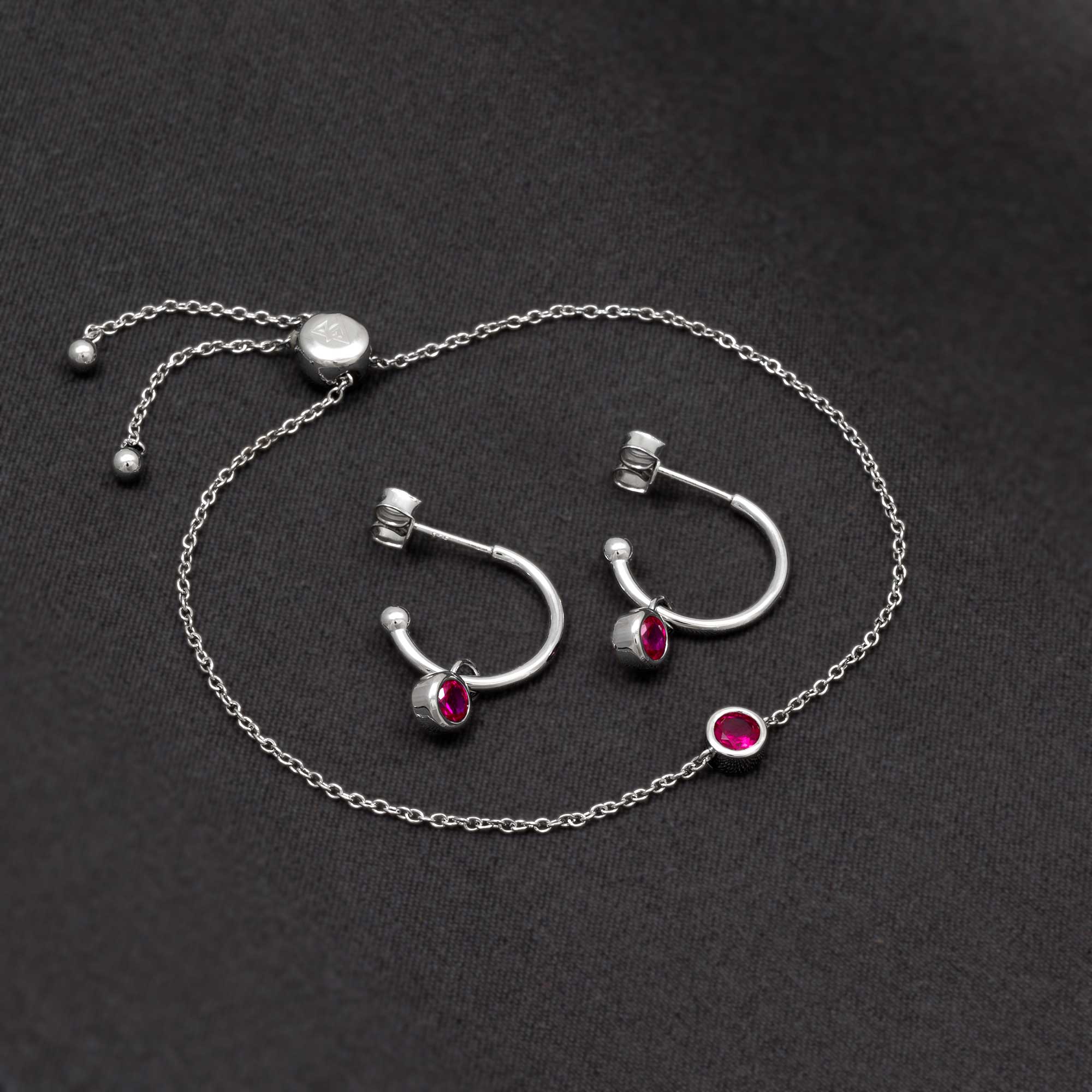 Sterling silver hoop earrings and delicate chain bracelet featuring deep red ruby gemstones, showcasing expert British design in contemporary sterling silver jewellery.