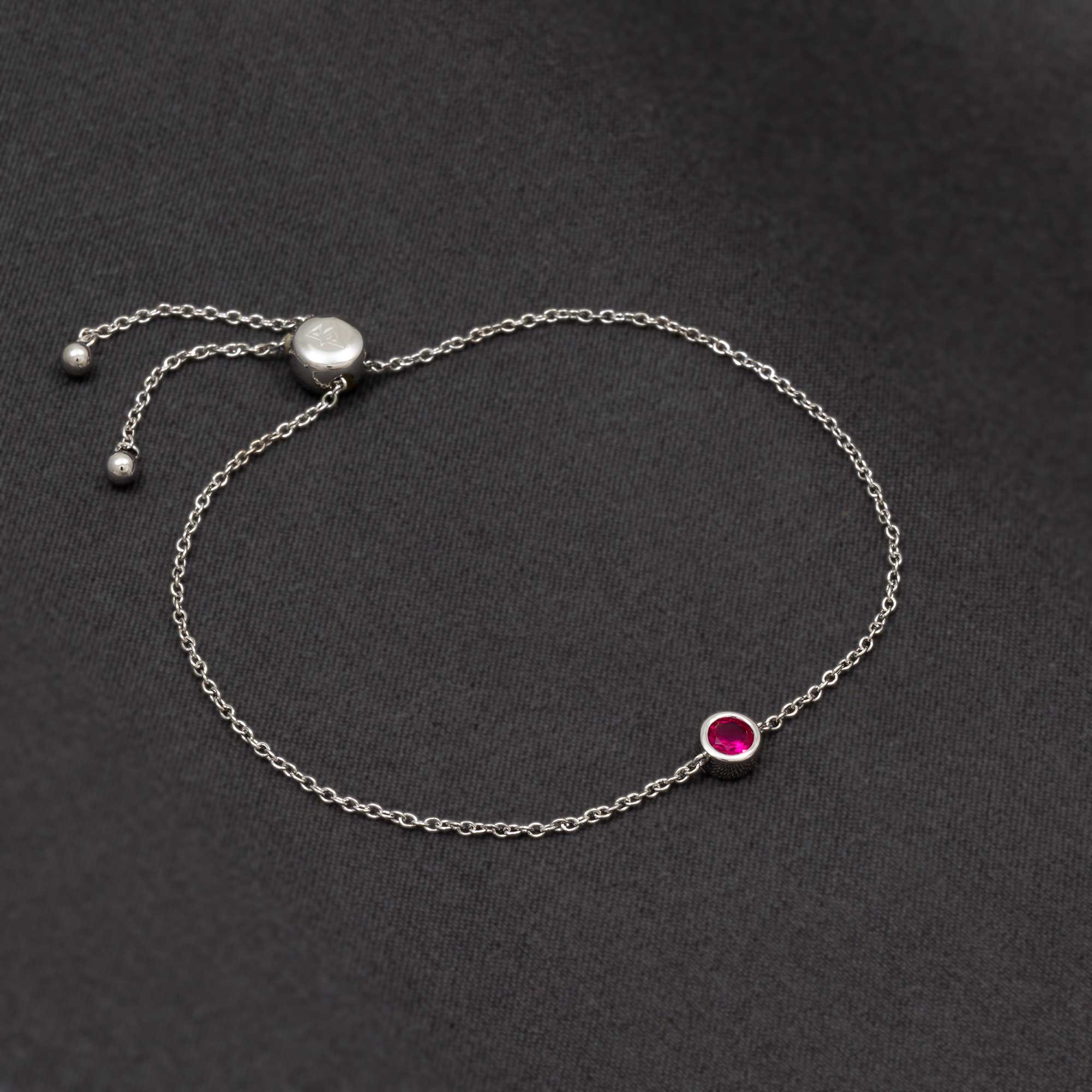 Delicate sterling silver bracelet featuring a vibrant ruby birthstone set in a bezel with an adjustable sliding clasp, exemplifying refined British craftsmanship.