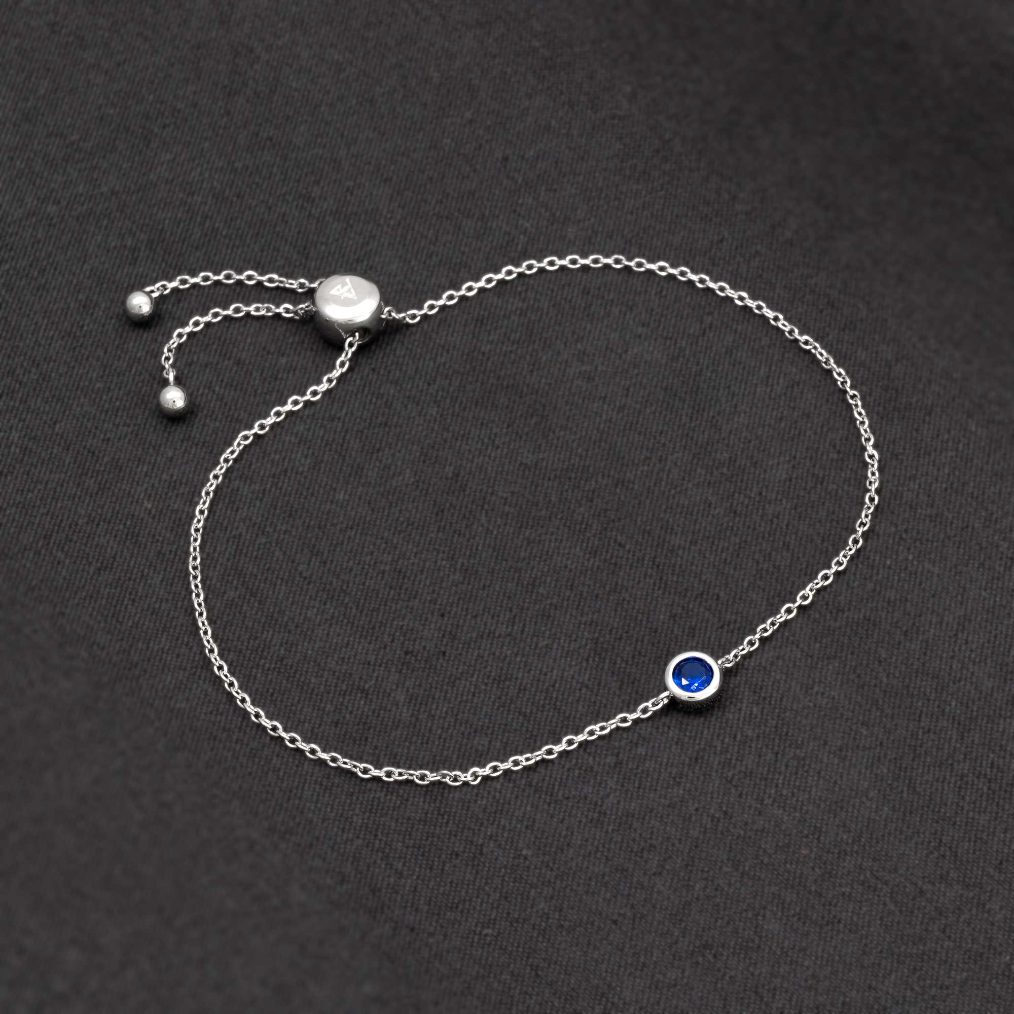 Adjustable sterling silver bracelet featuring a deep blue spinel birthstone set in a bezel on a fine chain, exemplifying refined British craftsmanship.