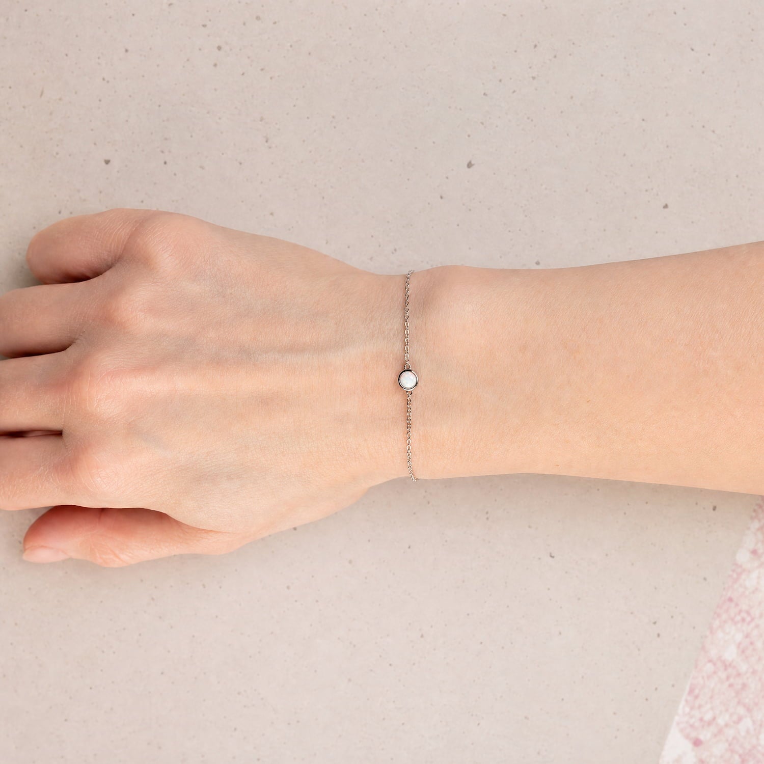 Delicate sterling silver bracelet featuring a single round opal centerpiece set on a fine adjustable chain, combining understated elegance with expert British craftsmanship.