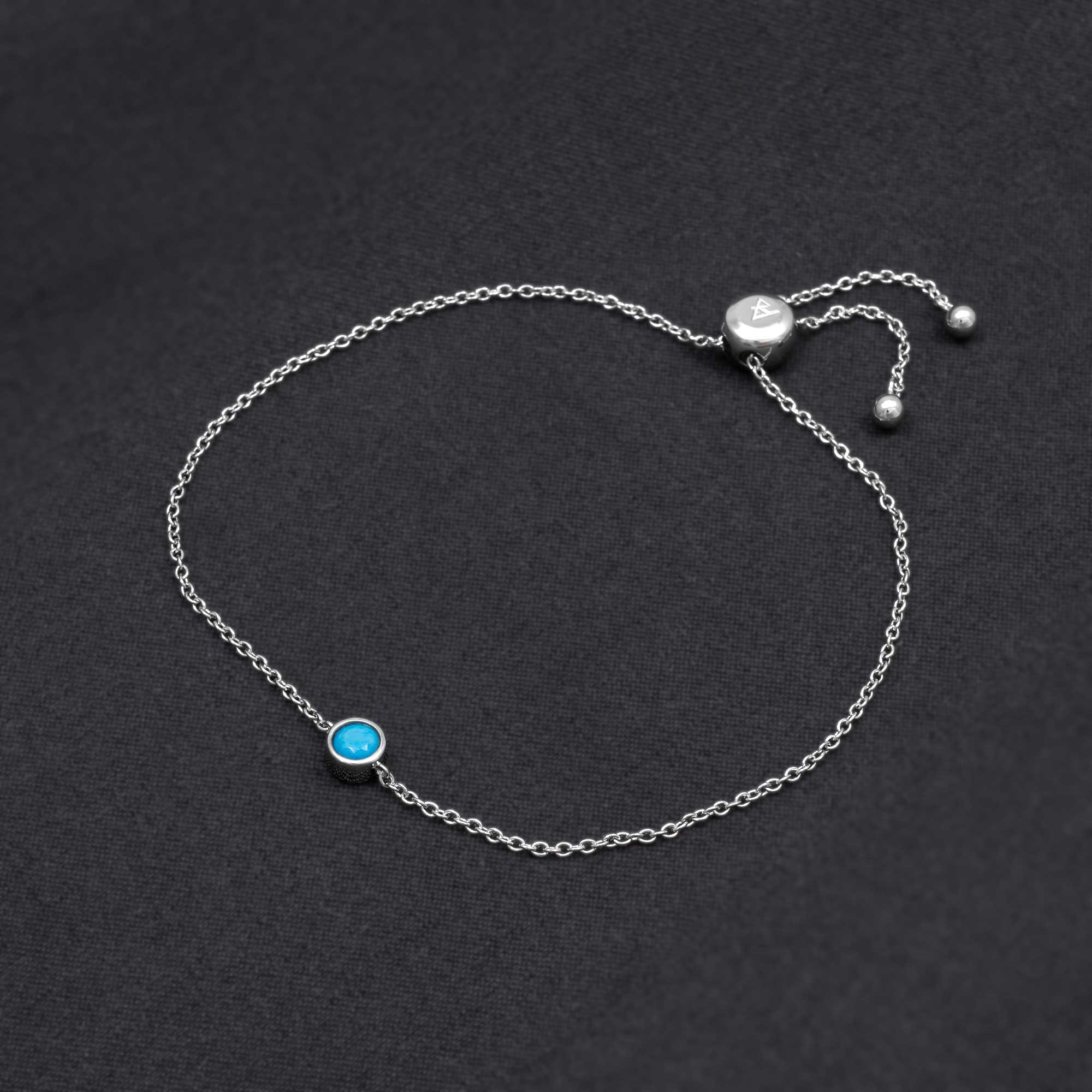 Delicate sterling silver bracelet featuring a vibrant turquoise birthstone set in a minimalist bezel with an adjustable sliding clasp, exemplifying refined British craftsmanship.