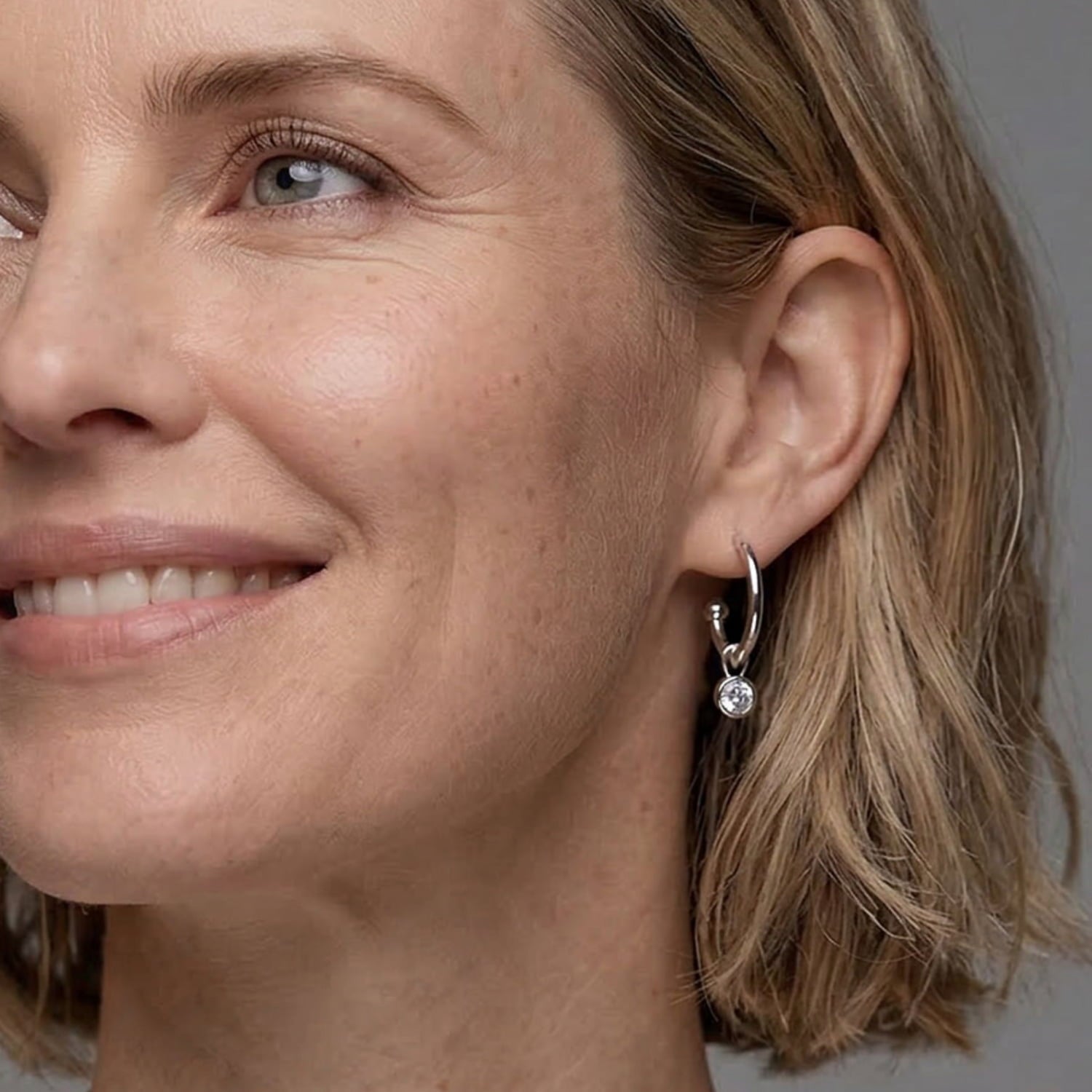 Delicate sterling silver hoop earrings featuring a single white topaz stone, combining contemporary elegance with expert British craftsmanship by Azendi.