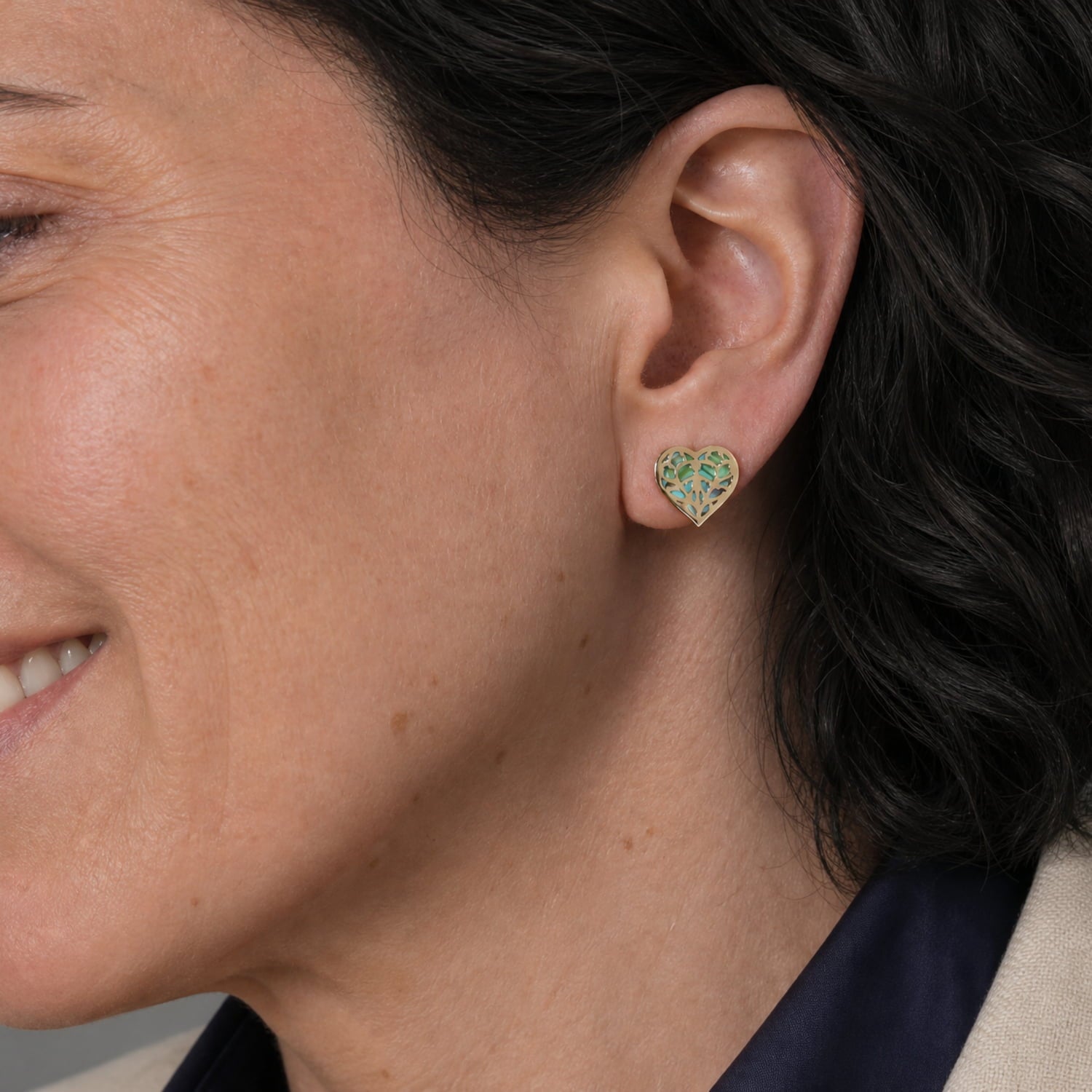 9 carat gold stud earrings featuring a heart-shaped openwork design with iridescent abalone inlay, combining delicate craftsmanship with a contemporary British aesthetic.