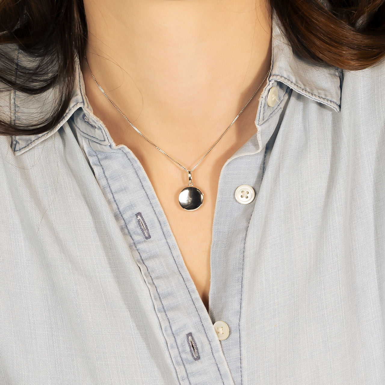 Polished sterling silver locket pendant on an adjustable delicate chain, featuring a smooth, reflective surface for a sleek and modern silhouette.