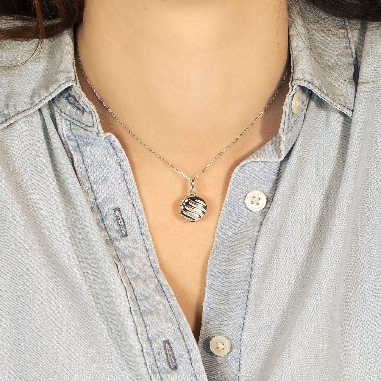 Sterling silver pendant featuring polished twist elements on a fine adjustable chain, styled against a light blue shirt for a modern, sculptural jewellery look.