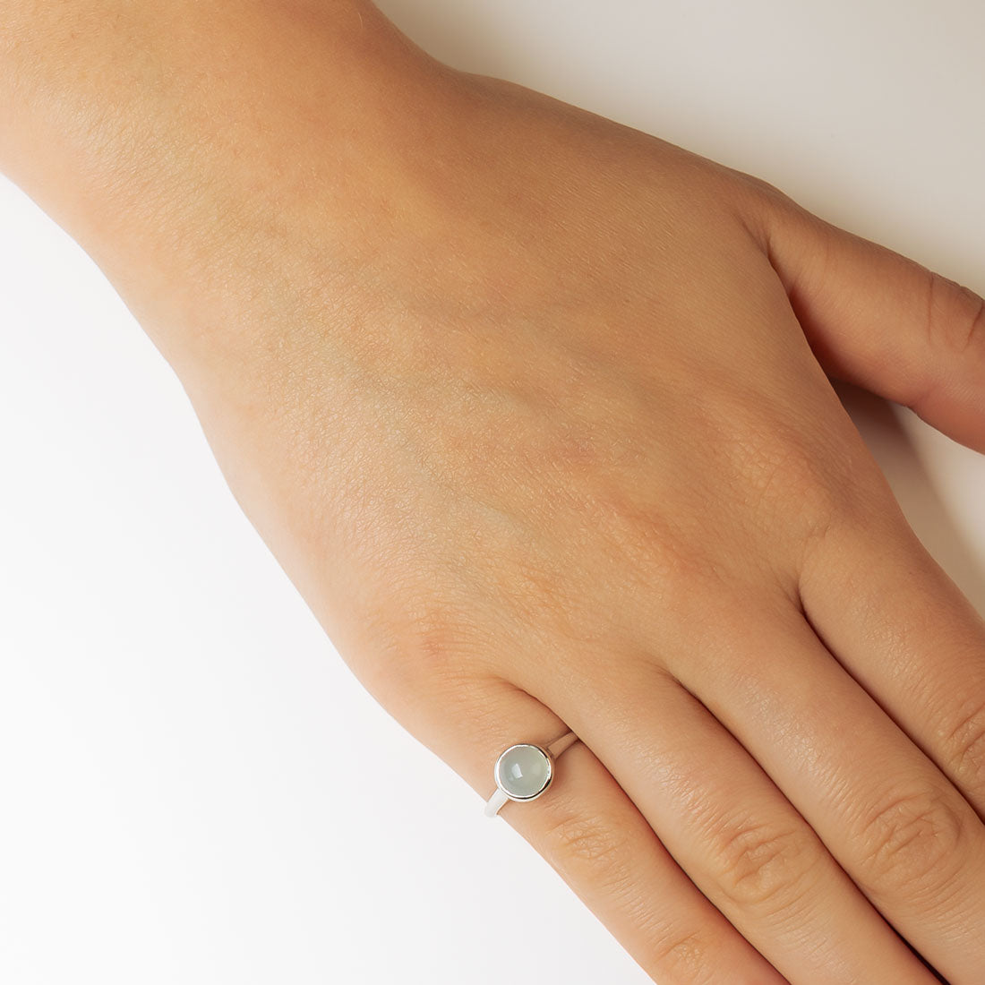 Hand wearing a sterling silver ring featuring a smooth round aqua chalcedony stone set in a polished bezel, showcasing minimalist and contemporary British jewellery design.