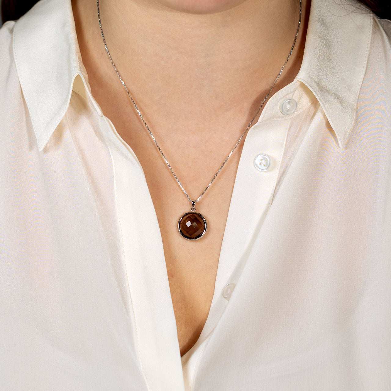 Sterling silver necklace featuring a checker cut smoky quartz pendant suspended on a fine chain, styled against a white blouse for a refined, contemporary look.