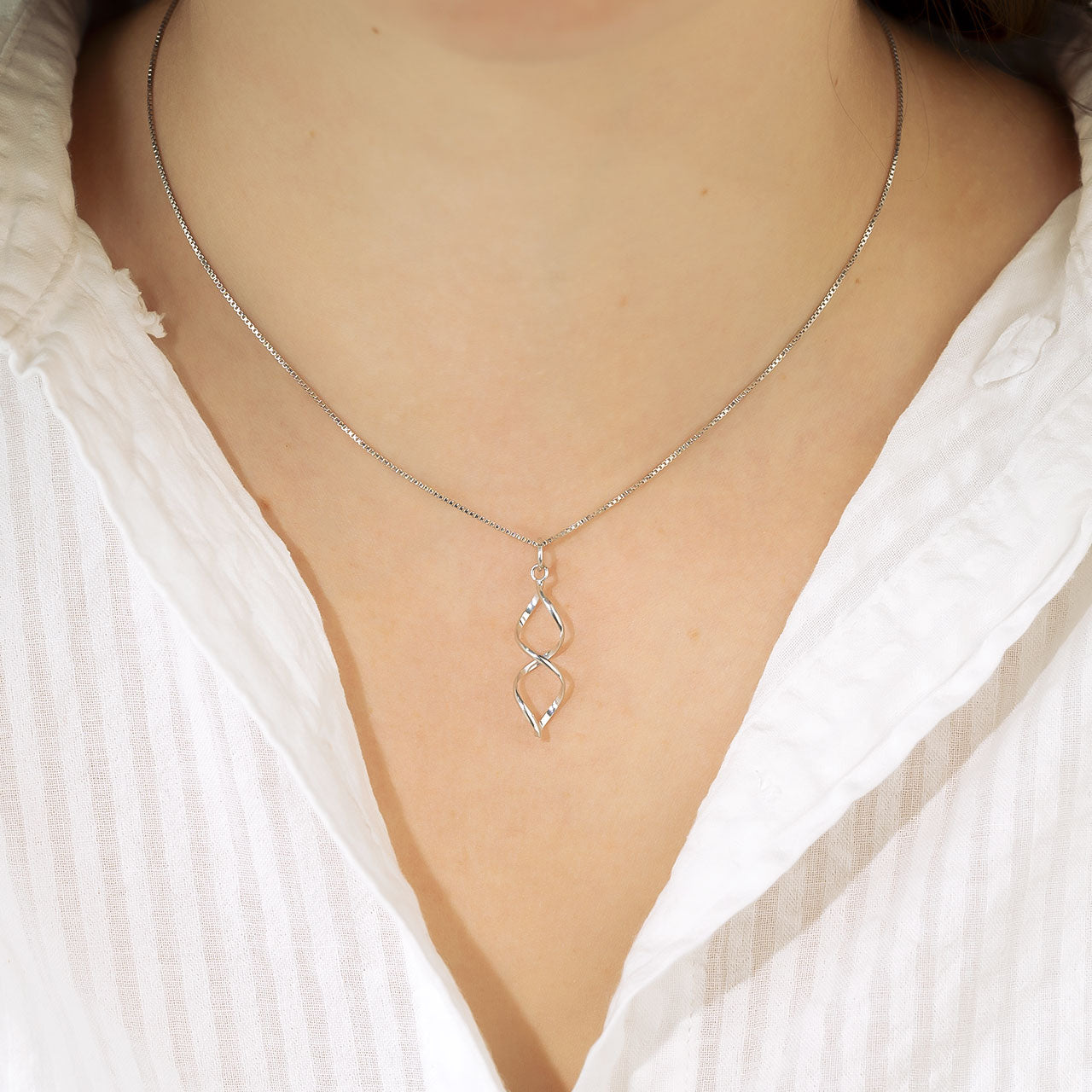 Sterling silver pendant featuring an elongated open twist design suspended from a fine chain, showcasing a modern sculptural style in contemporary silver jewellery.