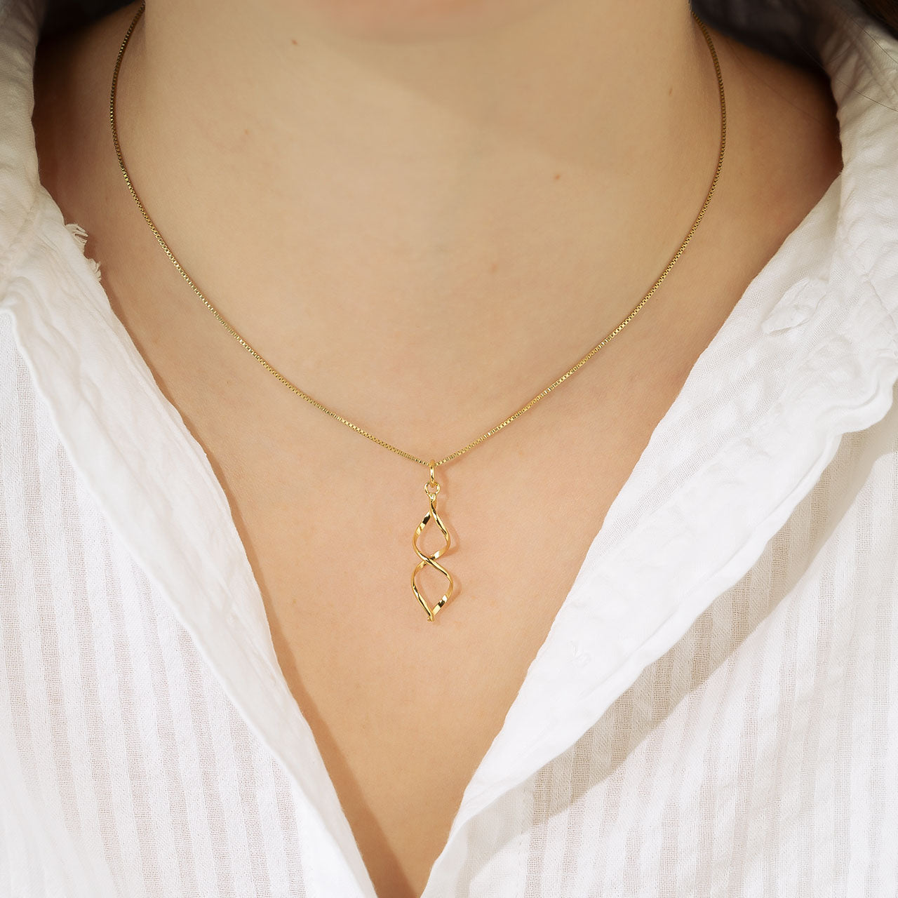 Delicate yellow gold vermeil pendant necklace featuring an elongated open twist design suspended from a fine chain, embodying contemporary and sculptural elegance.