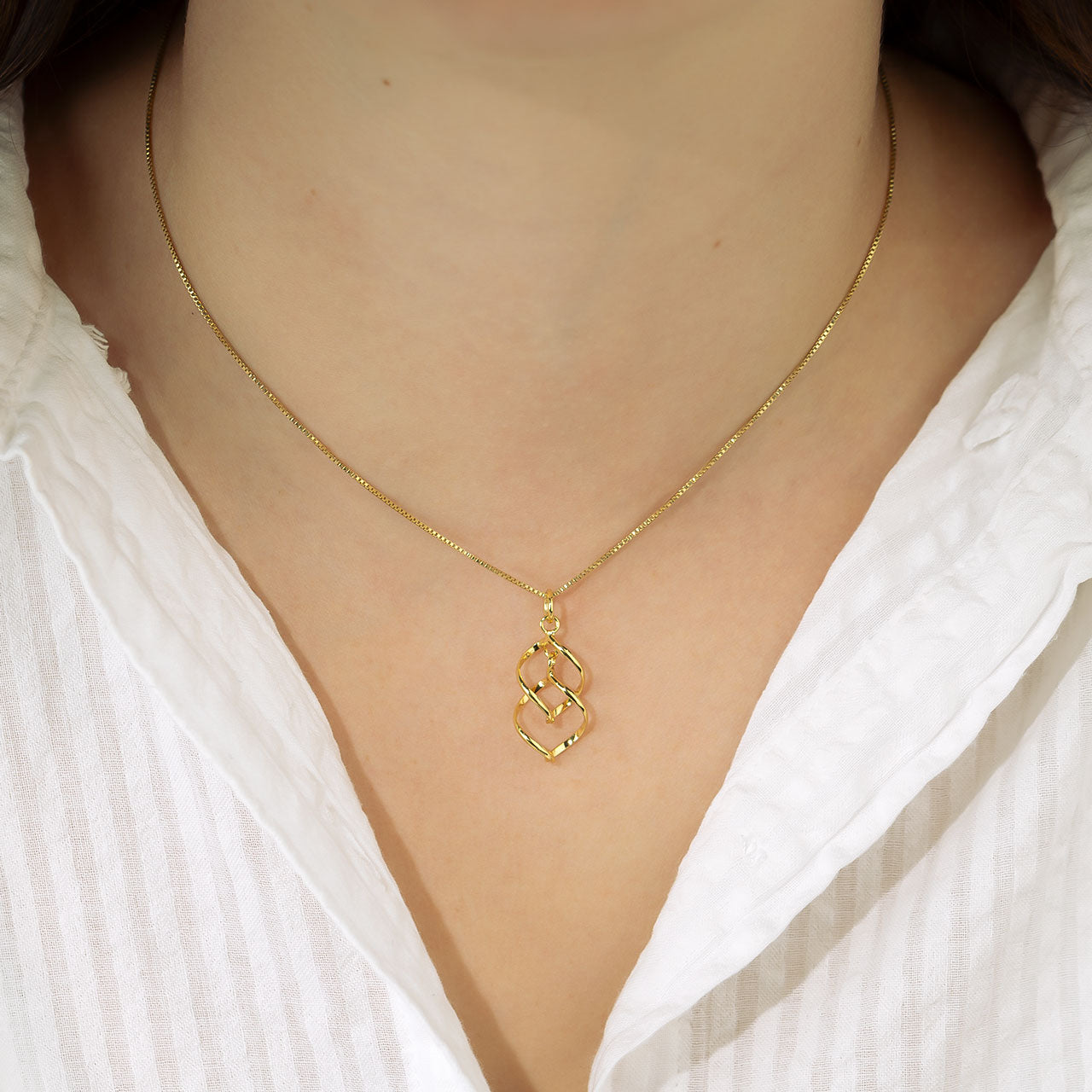 Delicate yellow gold vermeil pendant featuring a sculptural spiral wave design suspended from a fine chain, embodying contemporary elegance in designer gold vermeil jewellery.