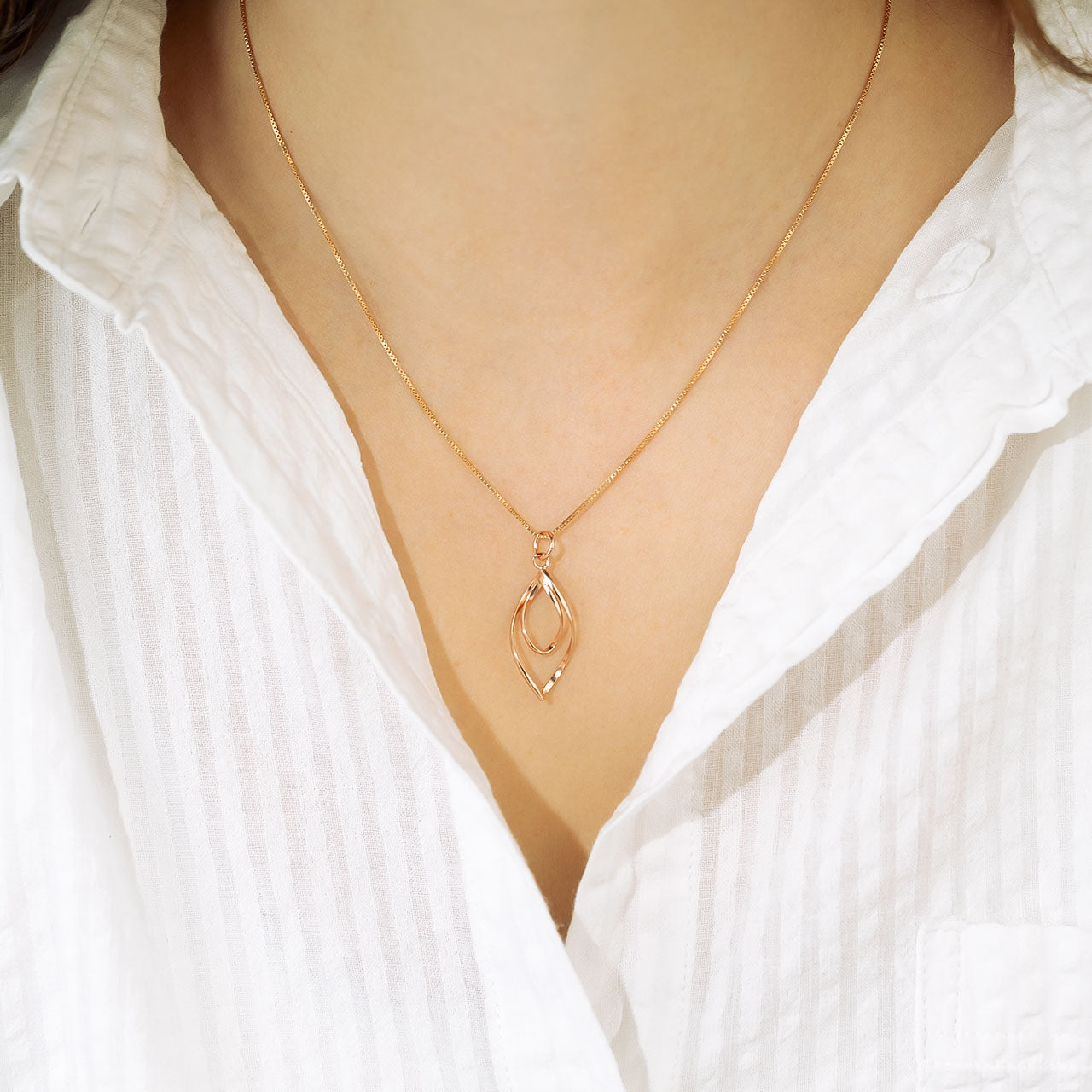 Elegant rose gold vermeil pendant featuring a sculptural spiral loop design suspended from a fine chain, highlighting refined craftsmanship in contemporary silver jewellery.