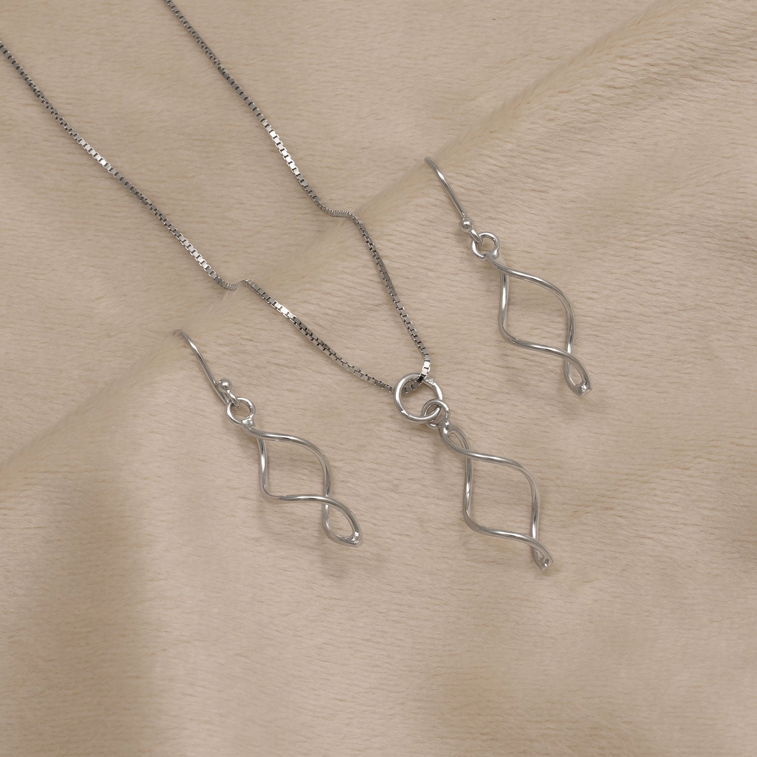 Delicate sterling silver drop earrings featuring an elegant twisted shape paired with a matching pendant necklace on a fine chain, exemplifying modern sculptural design.