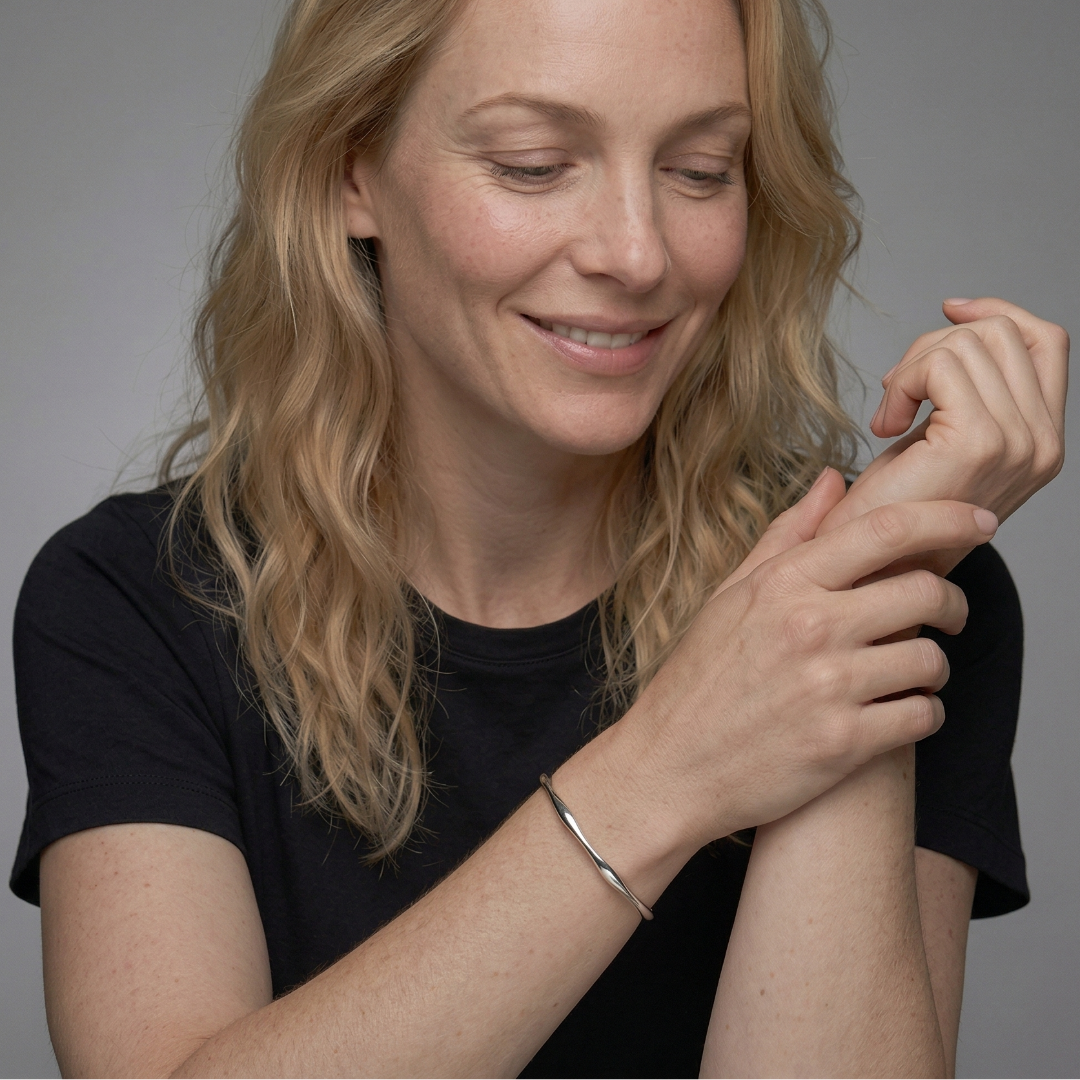 Minimalist sterling silver cuff bangle with a fluid wave design, showcasing sleek, polished curves that embody contemporary British silver jewellery craftsmanship.