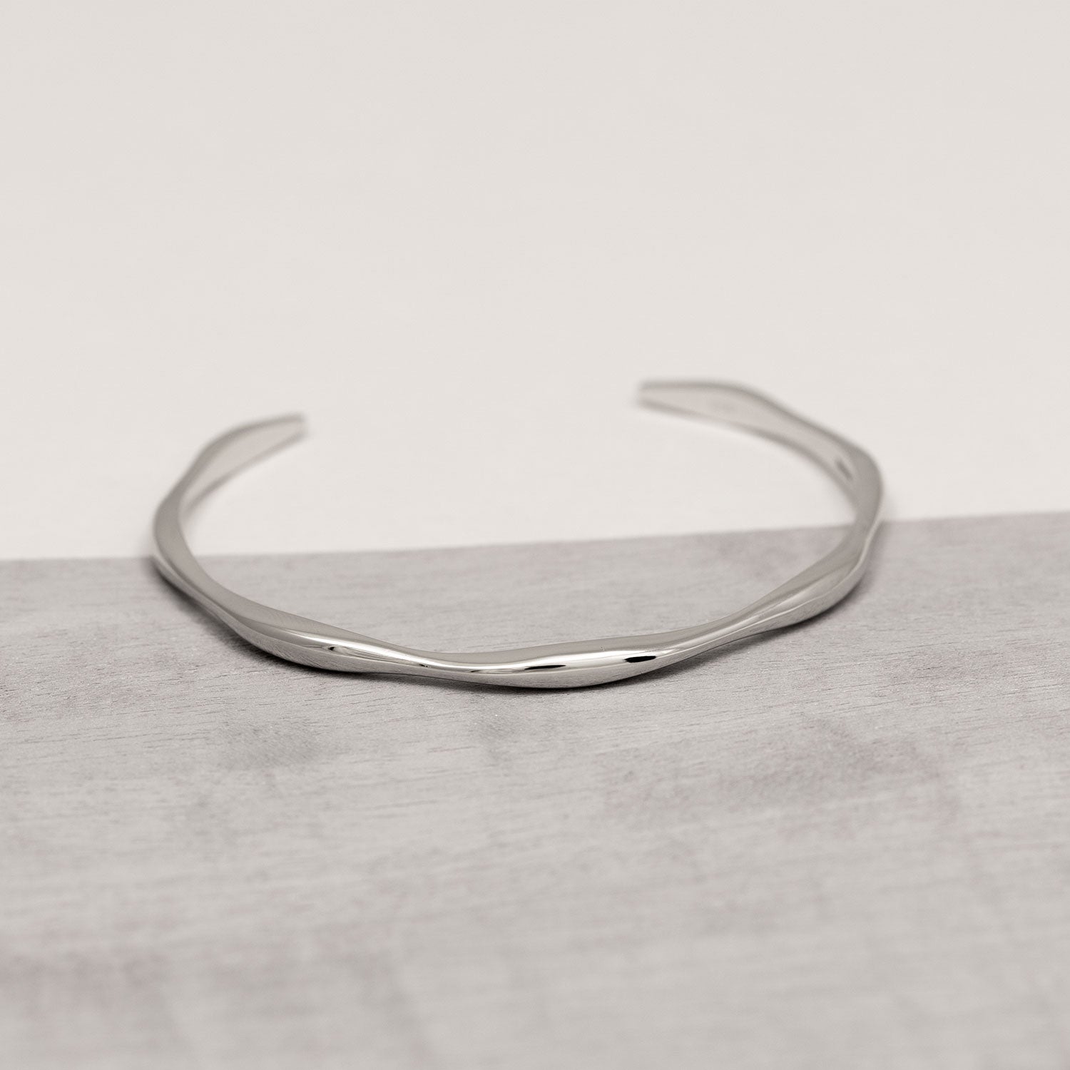 Sleek sterling silver cuff bracelet featuring a gently undulating wave design, combining minimalist elegance with a contemporary sculptural form in fine silver jewellery.