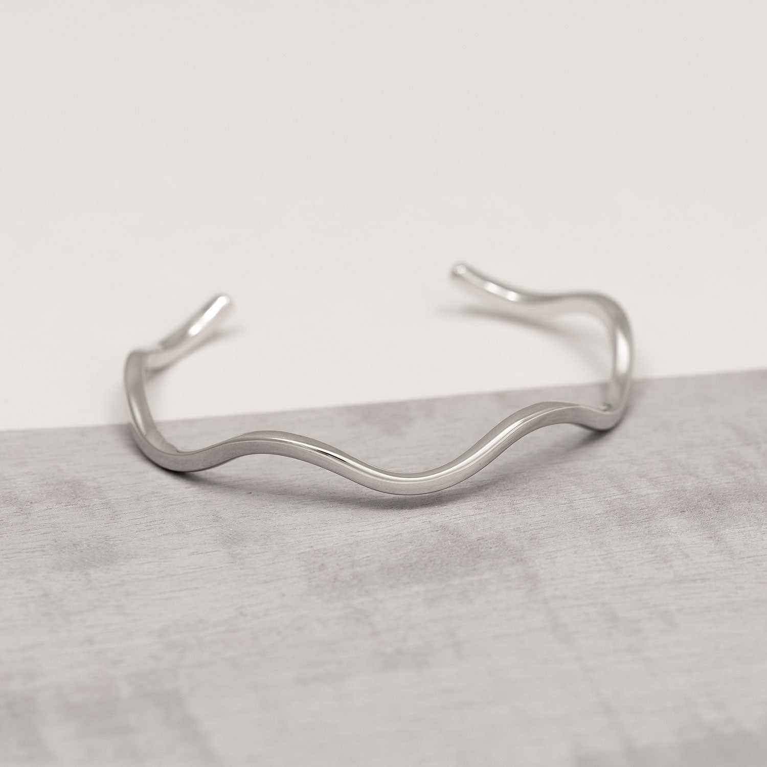 Delicately curved sterling silver cuff bracelet featuring smooth, flowing waves for a modern, sculptural look in polished silver jewellery.