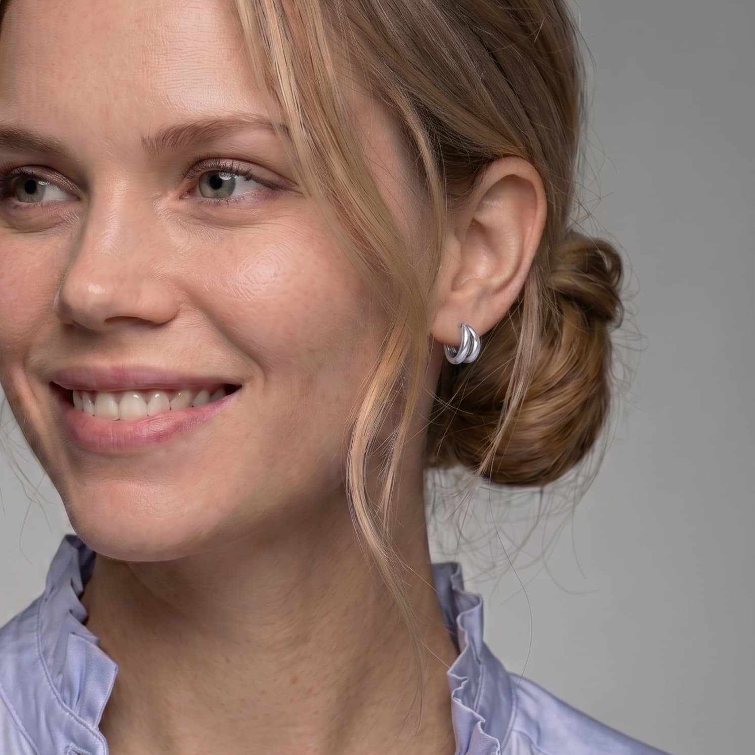 Model wears a minimalist pair of sterling silver double hinged hoop earrings featuring a smooth, sculptural design