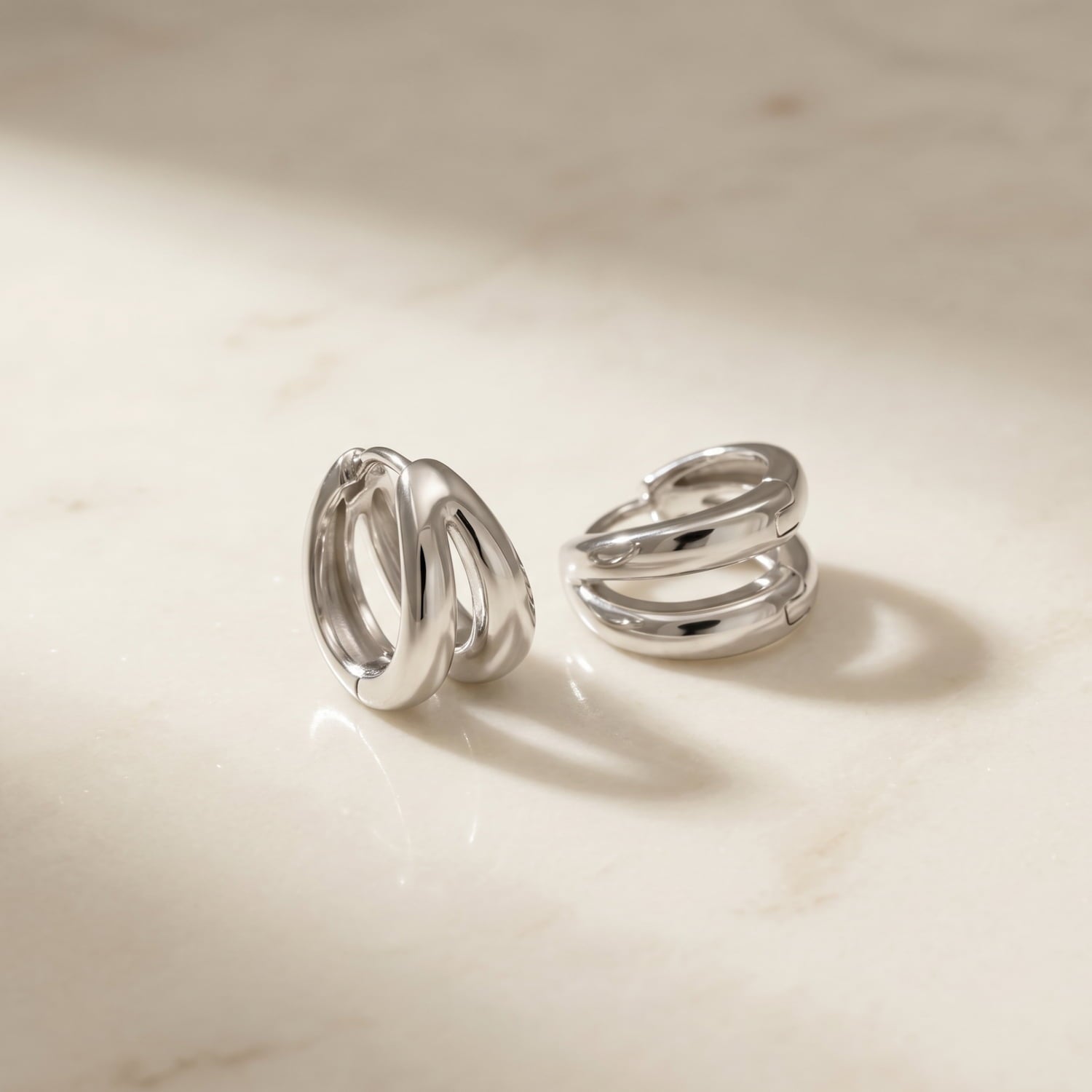 Doubled banded polished sterling silver hoop earrings displayed on a marble background.