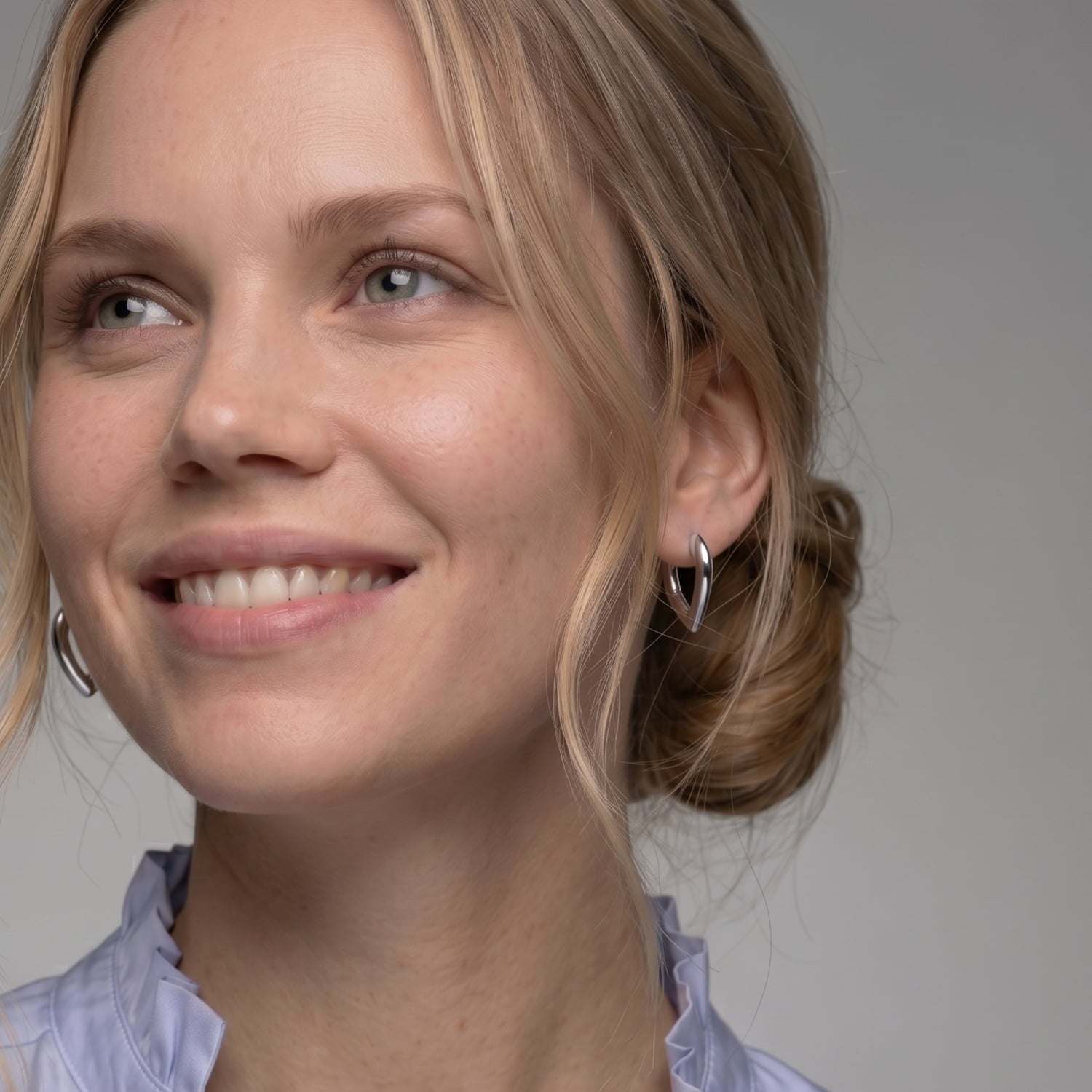 Miodel wears a pair of sculptural sterling silver hinged hoop earrings in a V-shaped design
