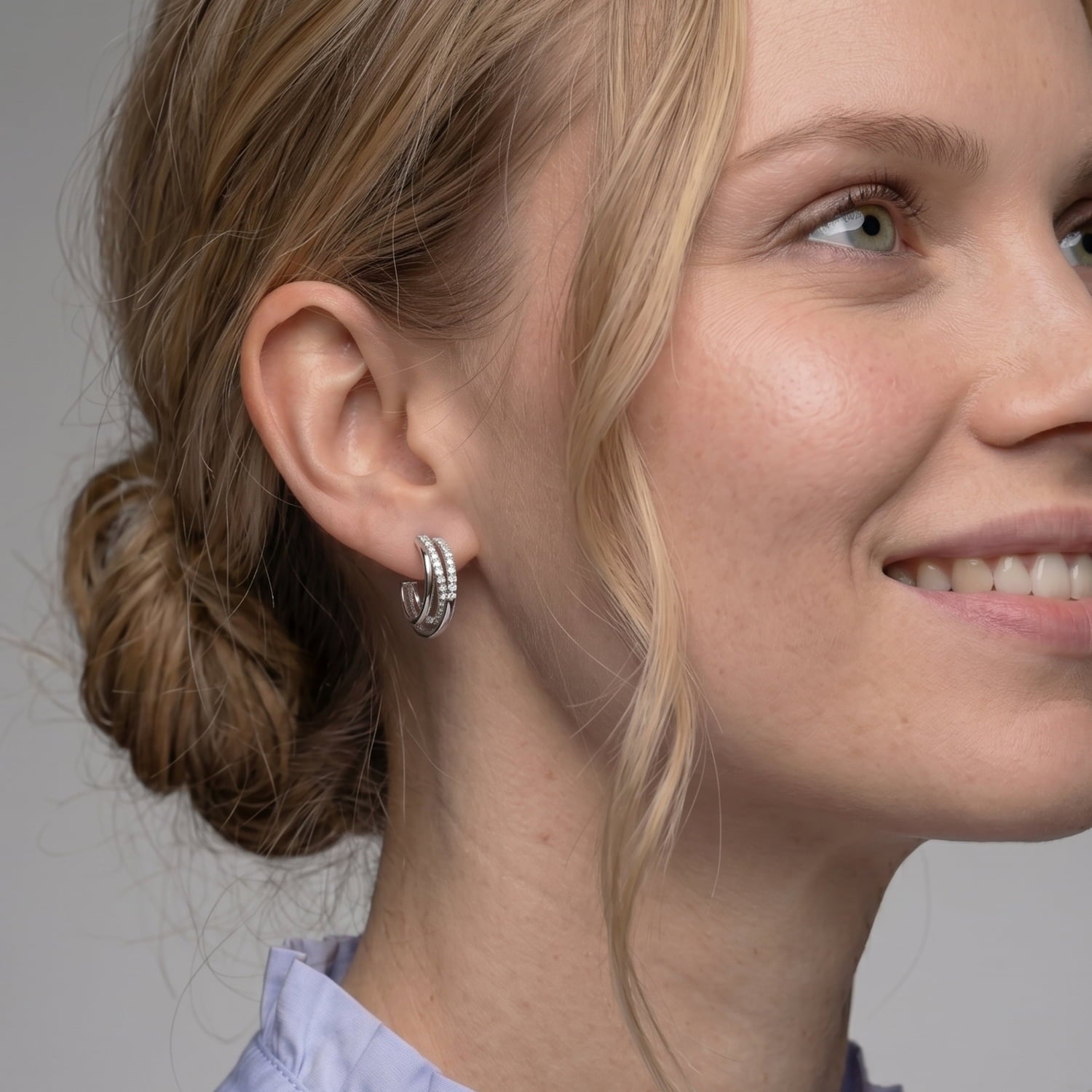 Model wears a pair of sterling silver hoop earrings featuring a four-strand crossover design with pavé-set stones