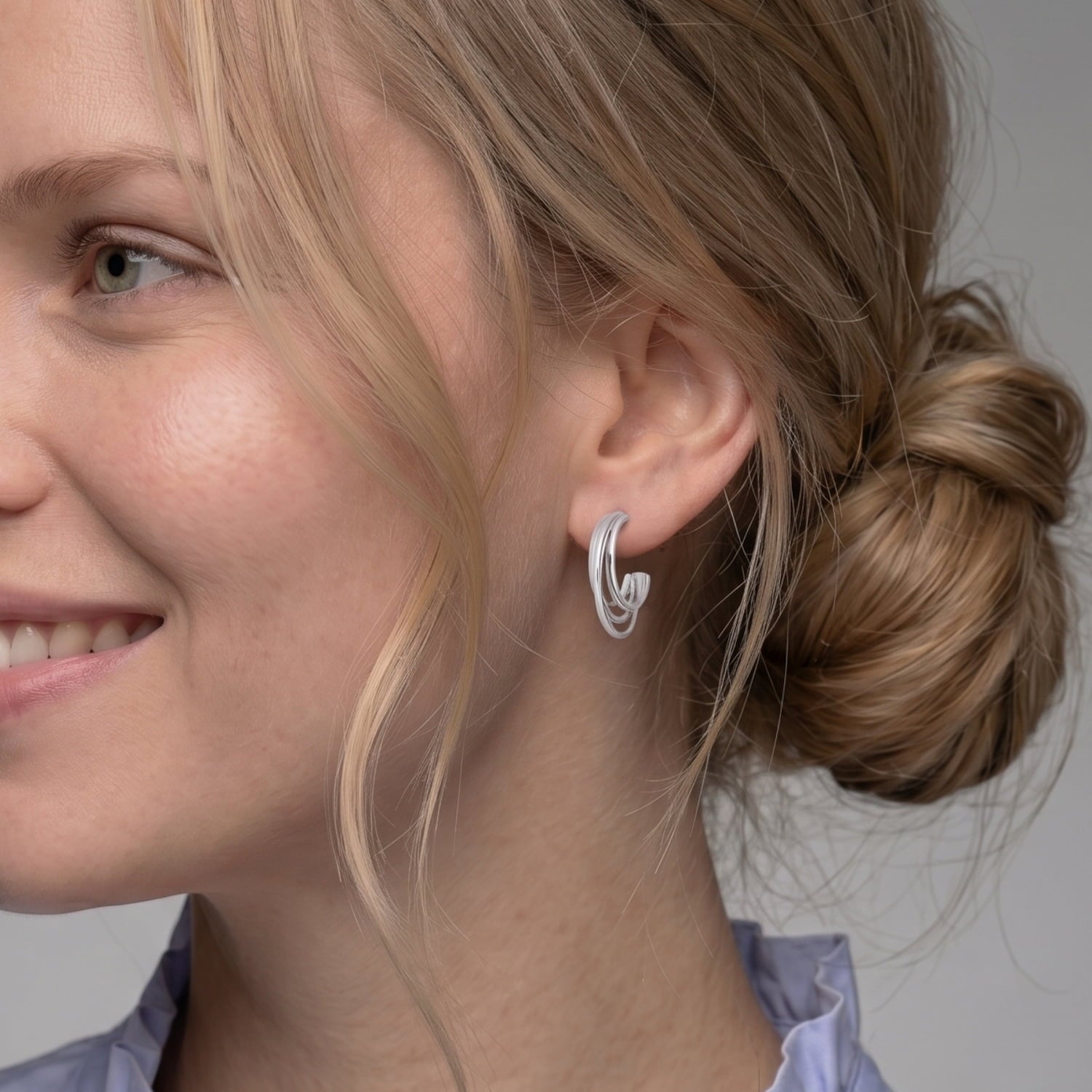 Model wears a pair of sterling silver hoop earrings featuring a sculptural four-strand design with a polished finish