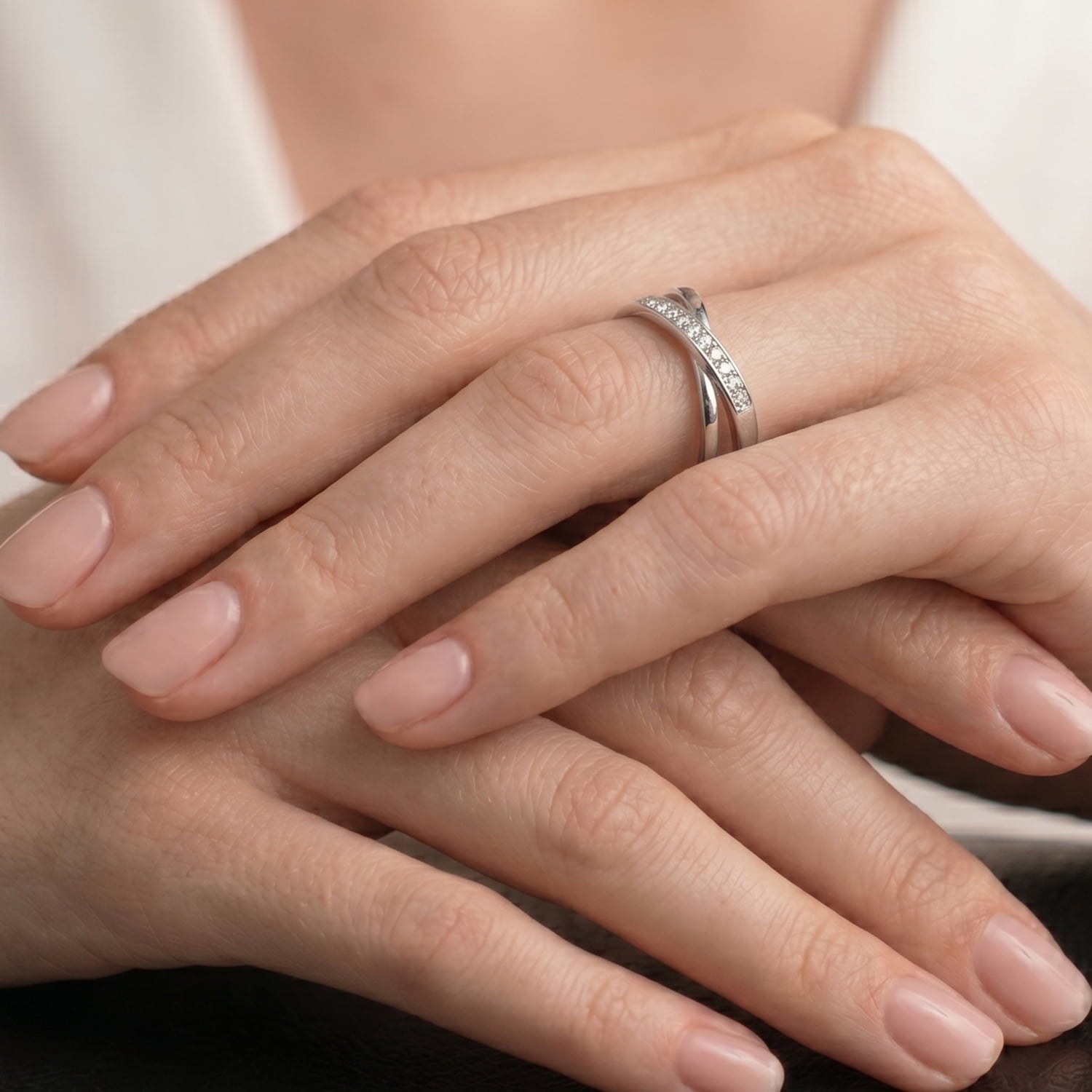 Model wears silver polished crossover ring, channel set with cubic zirconia stones.