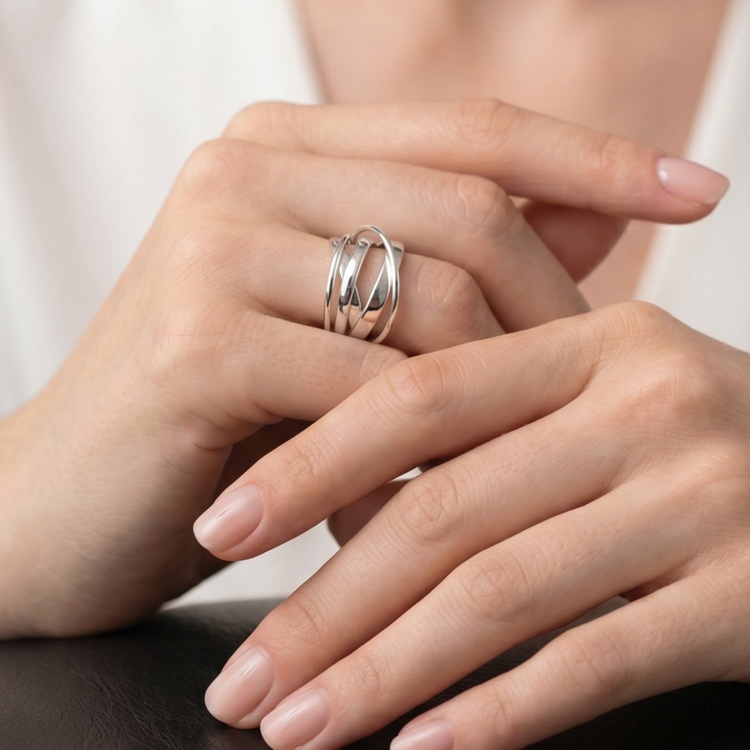 Close-up of a hand wearing a multistranded polished silver ring.
